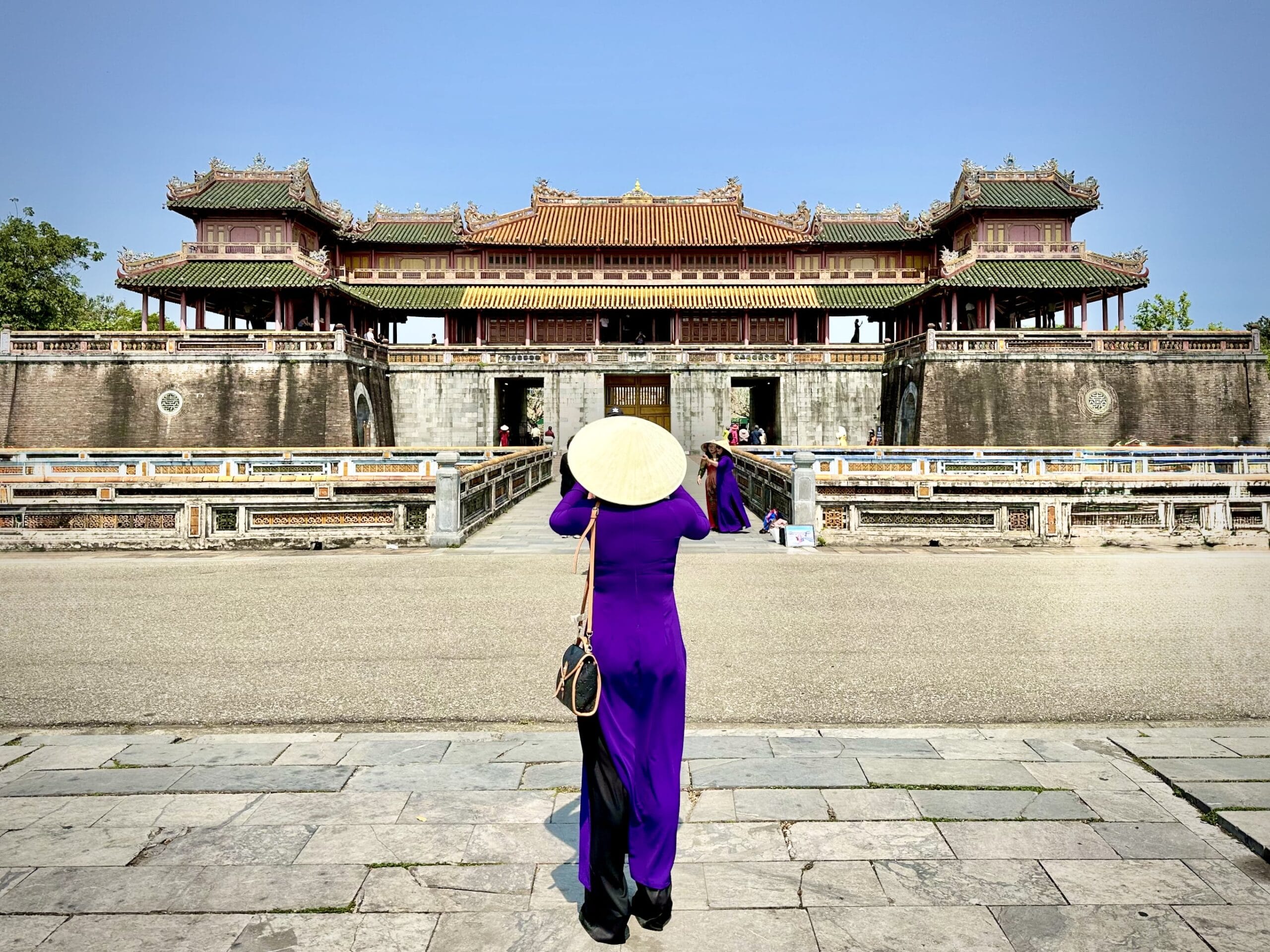 Woman in traditional dress in front of Hue Imperial Palace, Vietnam
