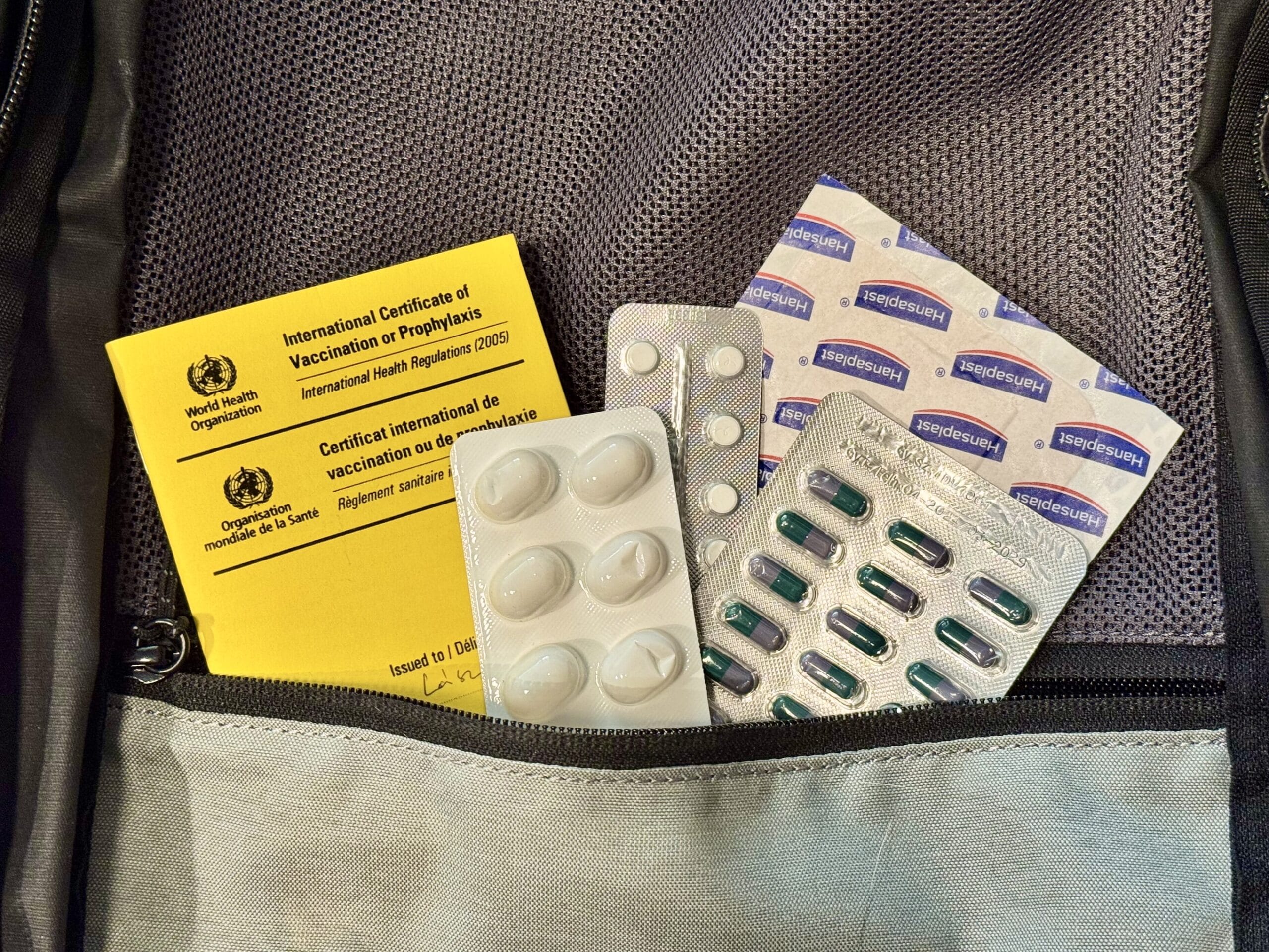 WHO Certificate of Vaccination and several medications in a travel bag.