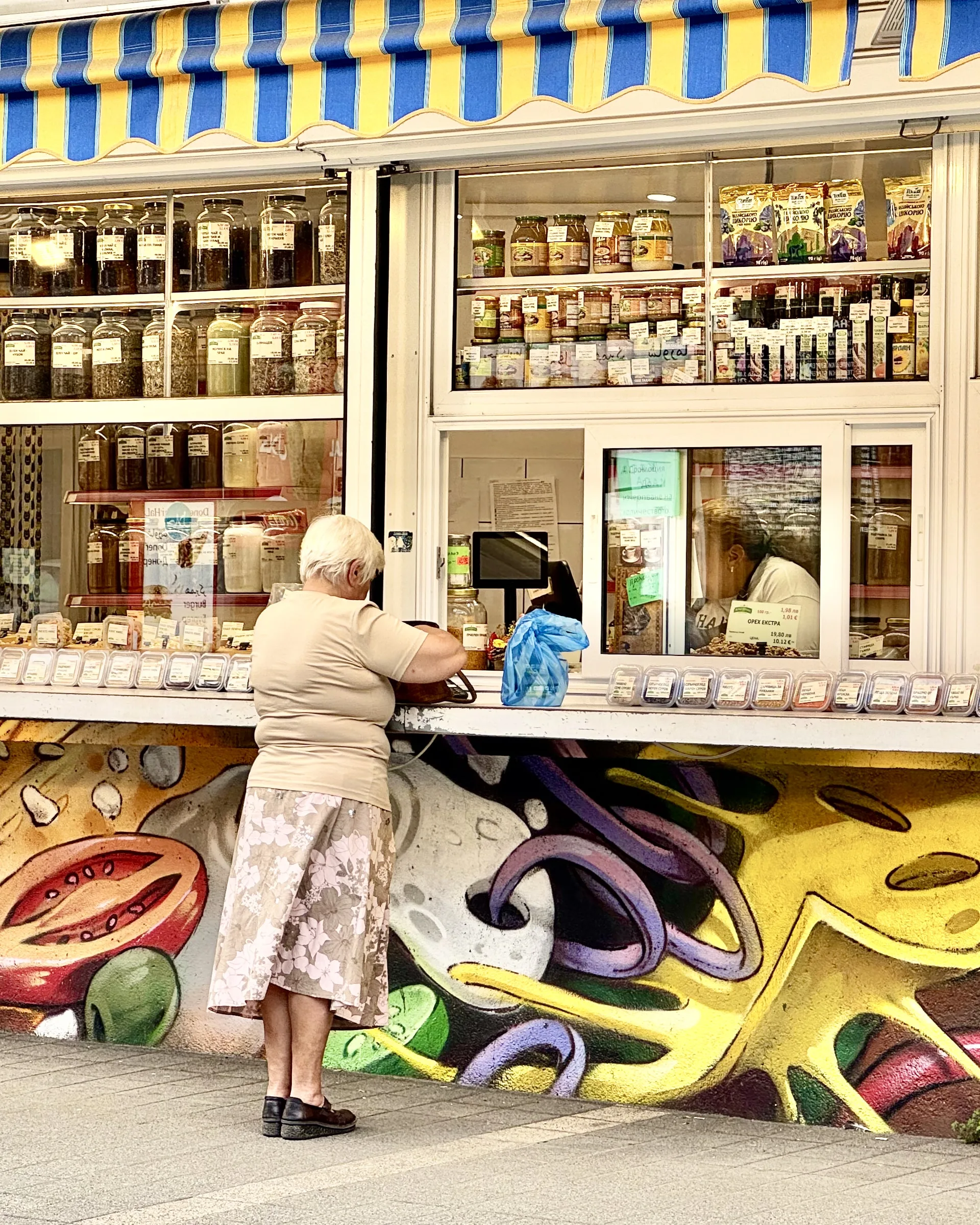 Babushka is shopping at one of the stalls in the market.