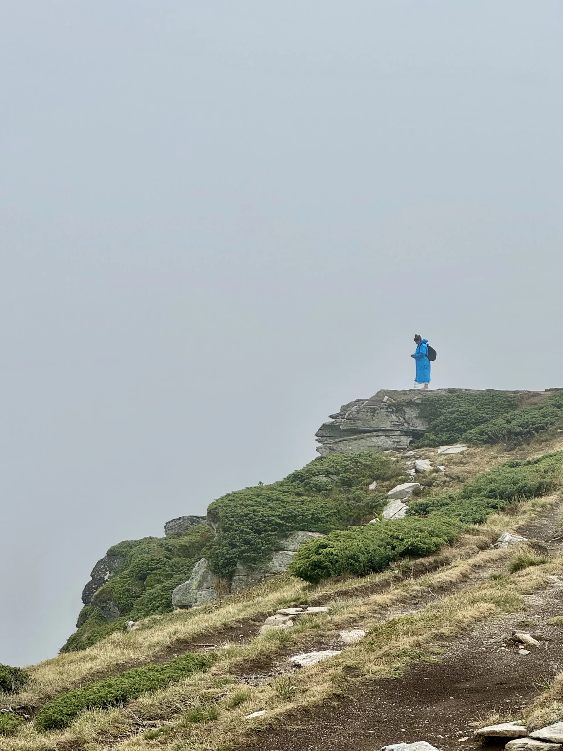 A lone hiker at a lookout point in the fog