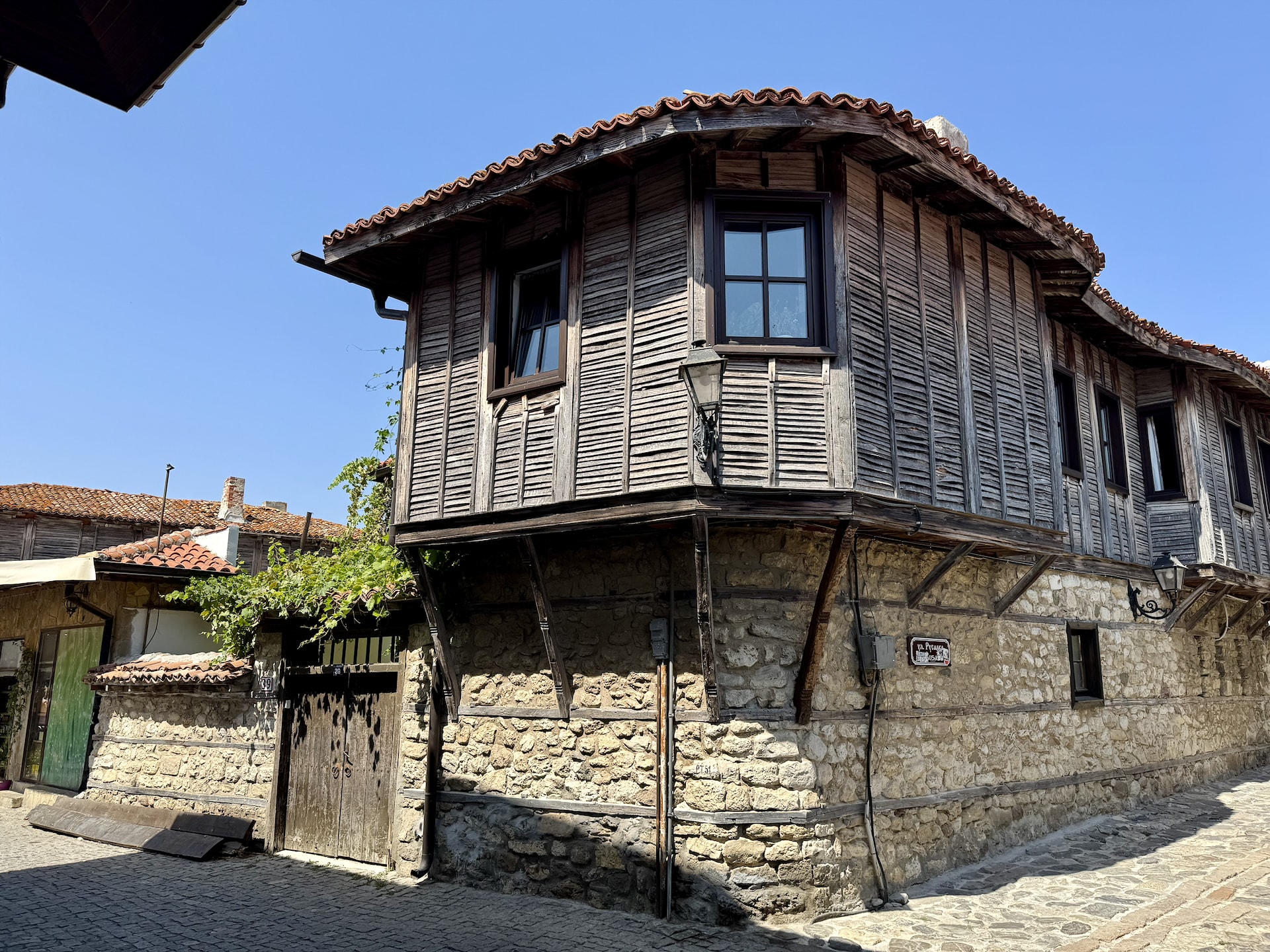Traditional Bulgarian Revival house on the corner of a cobblestone street.