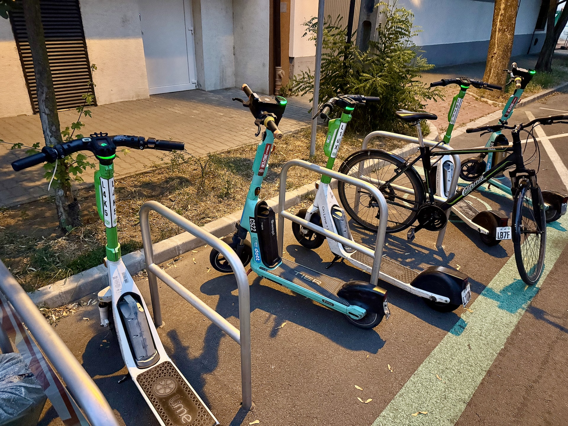 Lime and Tier e-scooters at a suburban scooter parking area at night.