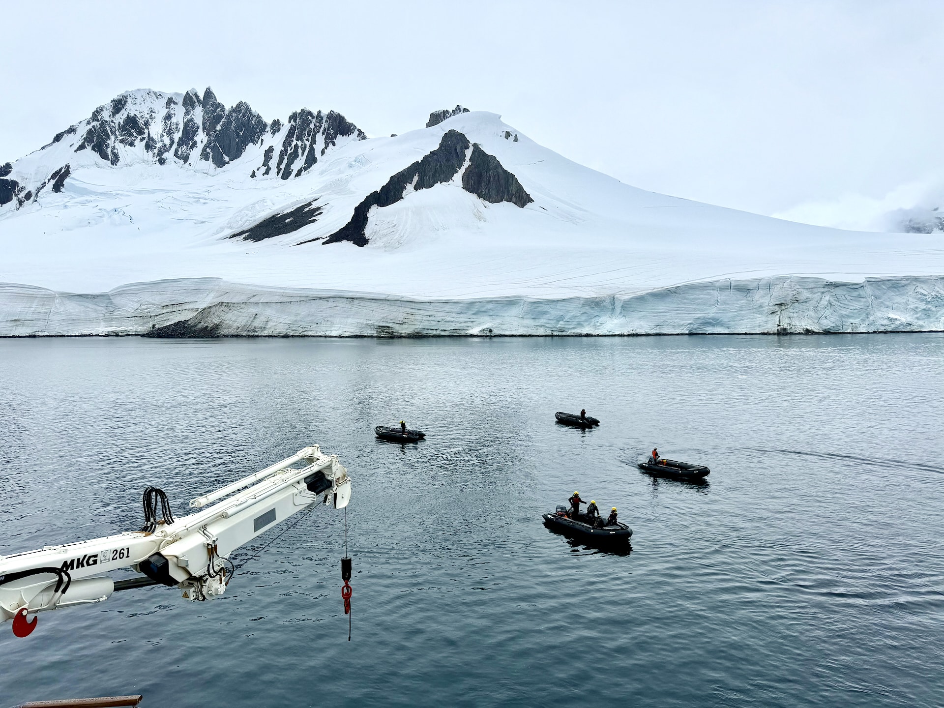 Zodiacs in the water before a landing operation – one of the ship's two davit cranes is visible in the corner