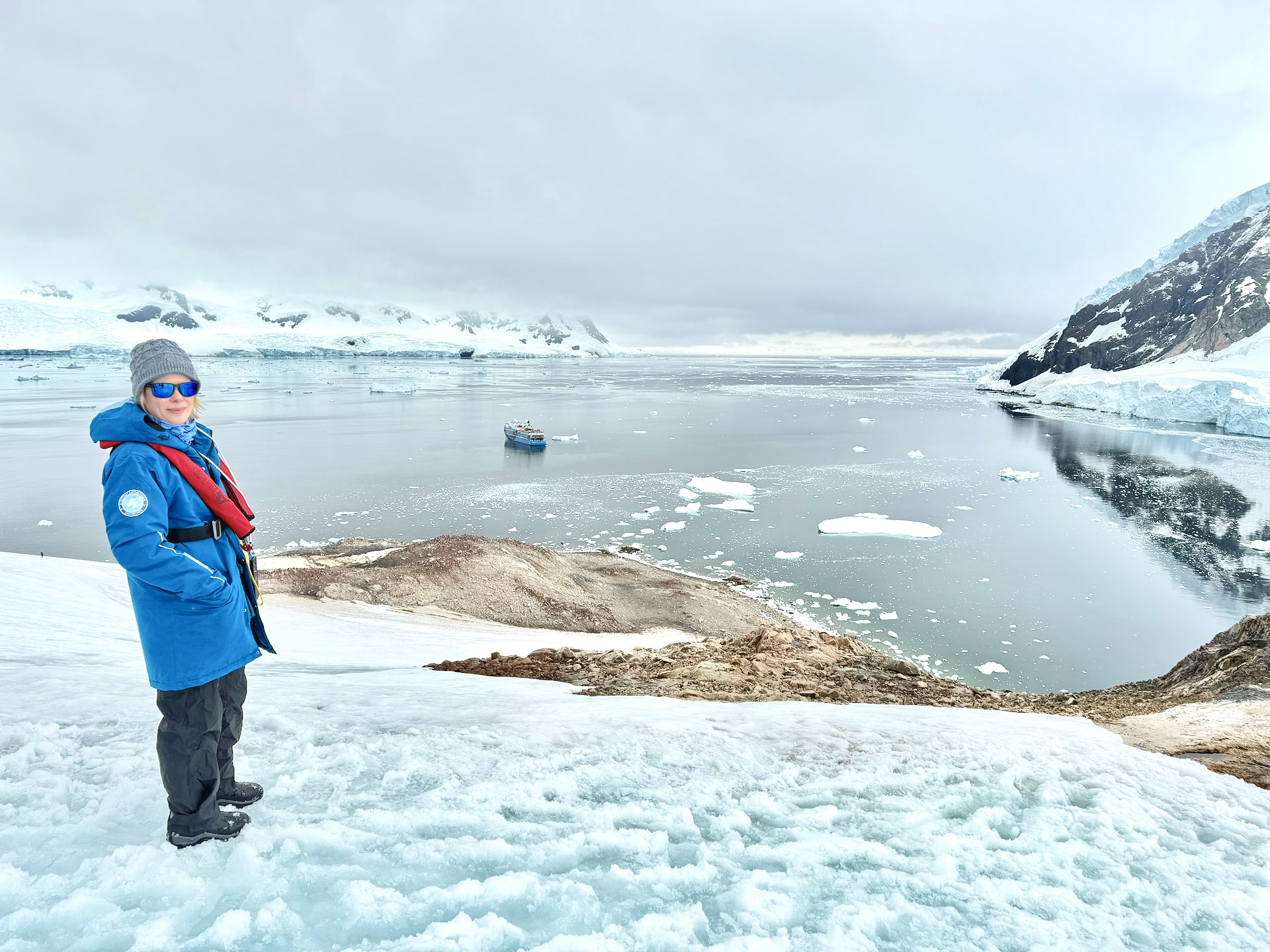 Andrea in the foreground, with the Ocean Albatros dwarfed by the Antarctic landscape behind her