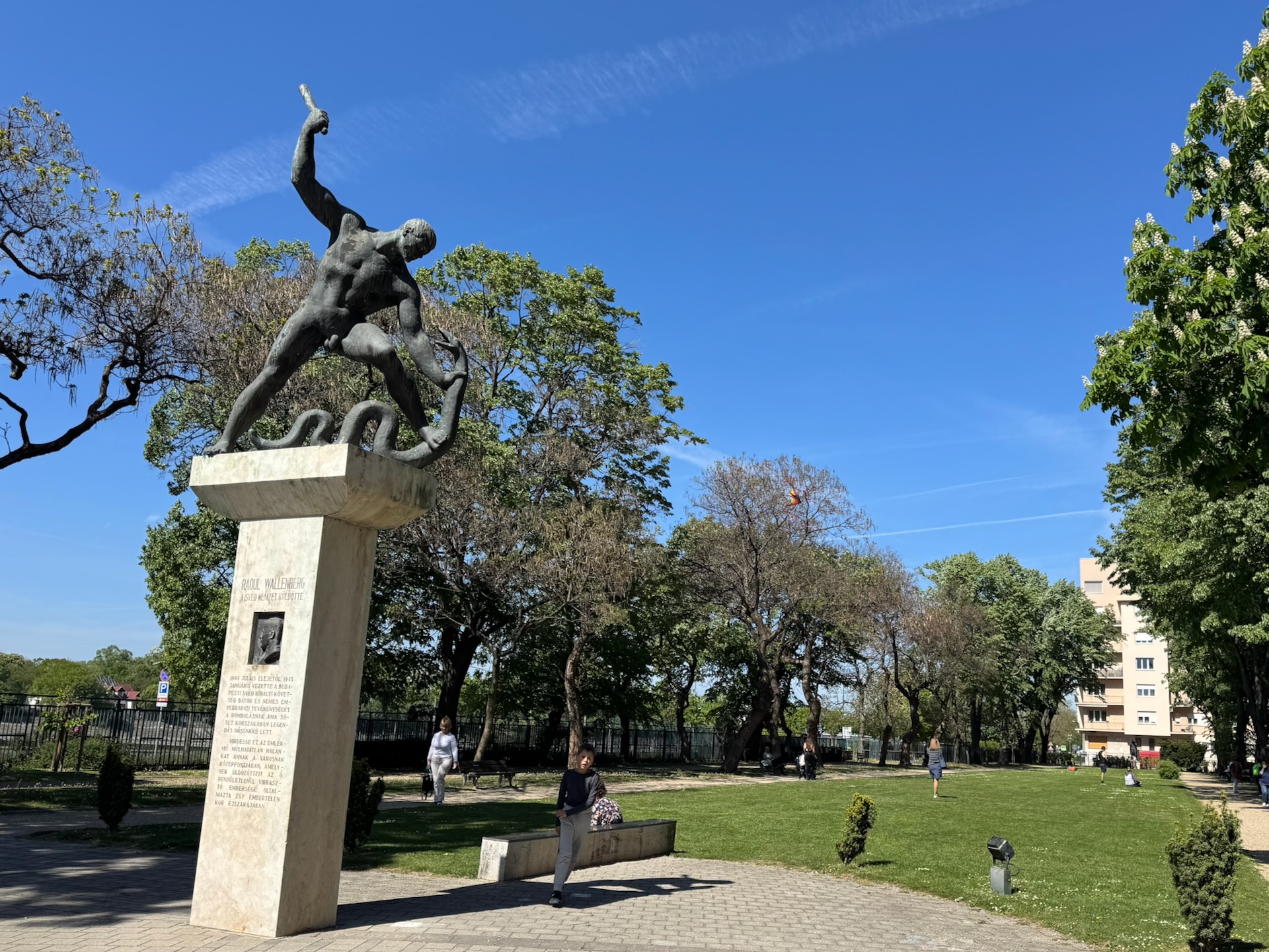 Wallenberg memorial sculpture of man wrestling serpent in Szent István Park Budapest with people sitting nearby