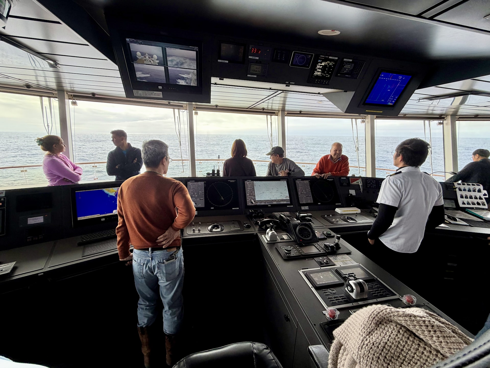 Open Bridge program on the Ocean Albatros showing passengers asking questions of a navigation officer at the bridge controls