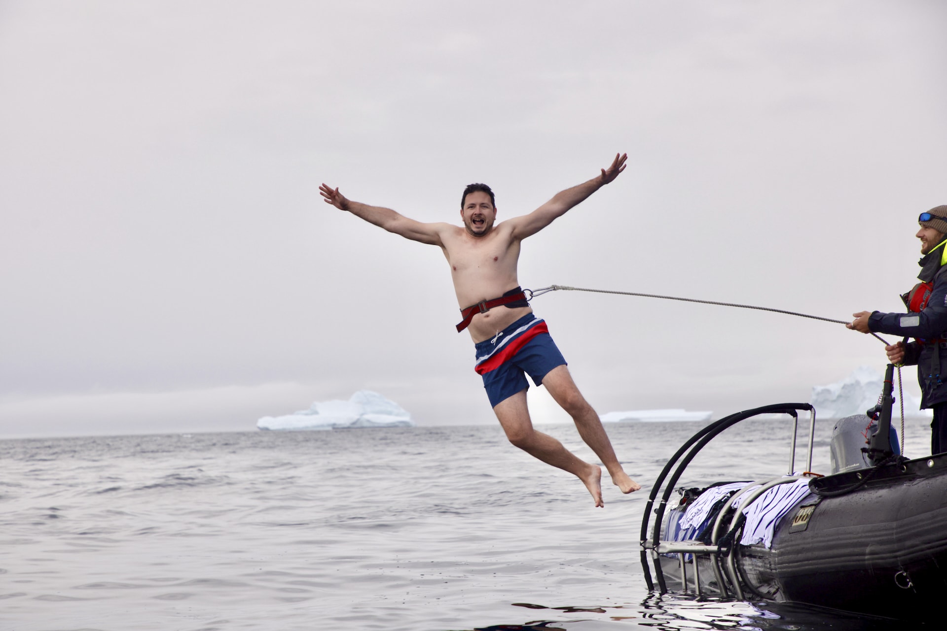 Polar Plunge in Antarctica: cruise passenger jumping from the Zodiac platform into the freezing Antarctic Ocean