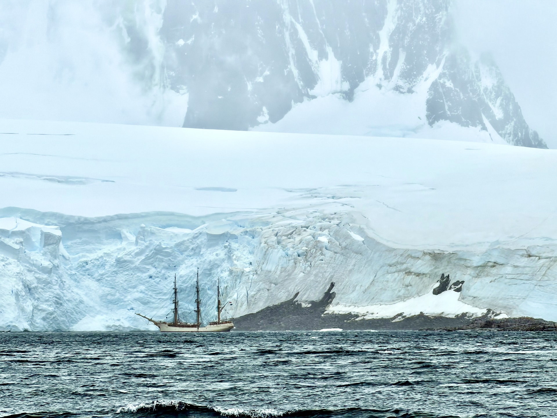 Three-masted tall ship anchored off Port Lockroy on the Antarctic Peninsula in worsening weather