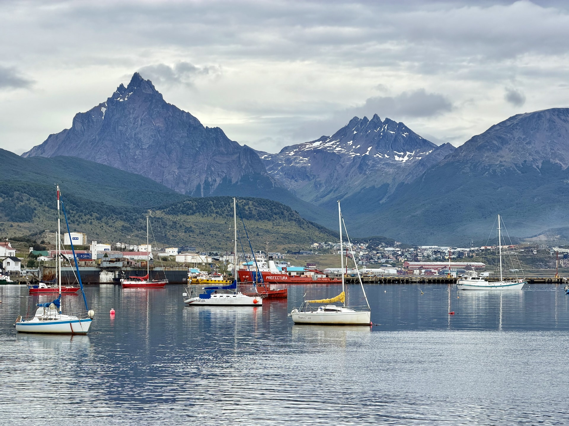 Ushuaia harbor with sailing boats moored in the foreground, mountains of Tierra del Fuego in the background