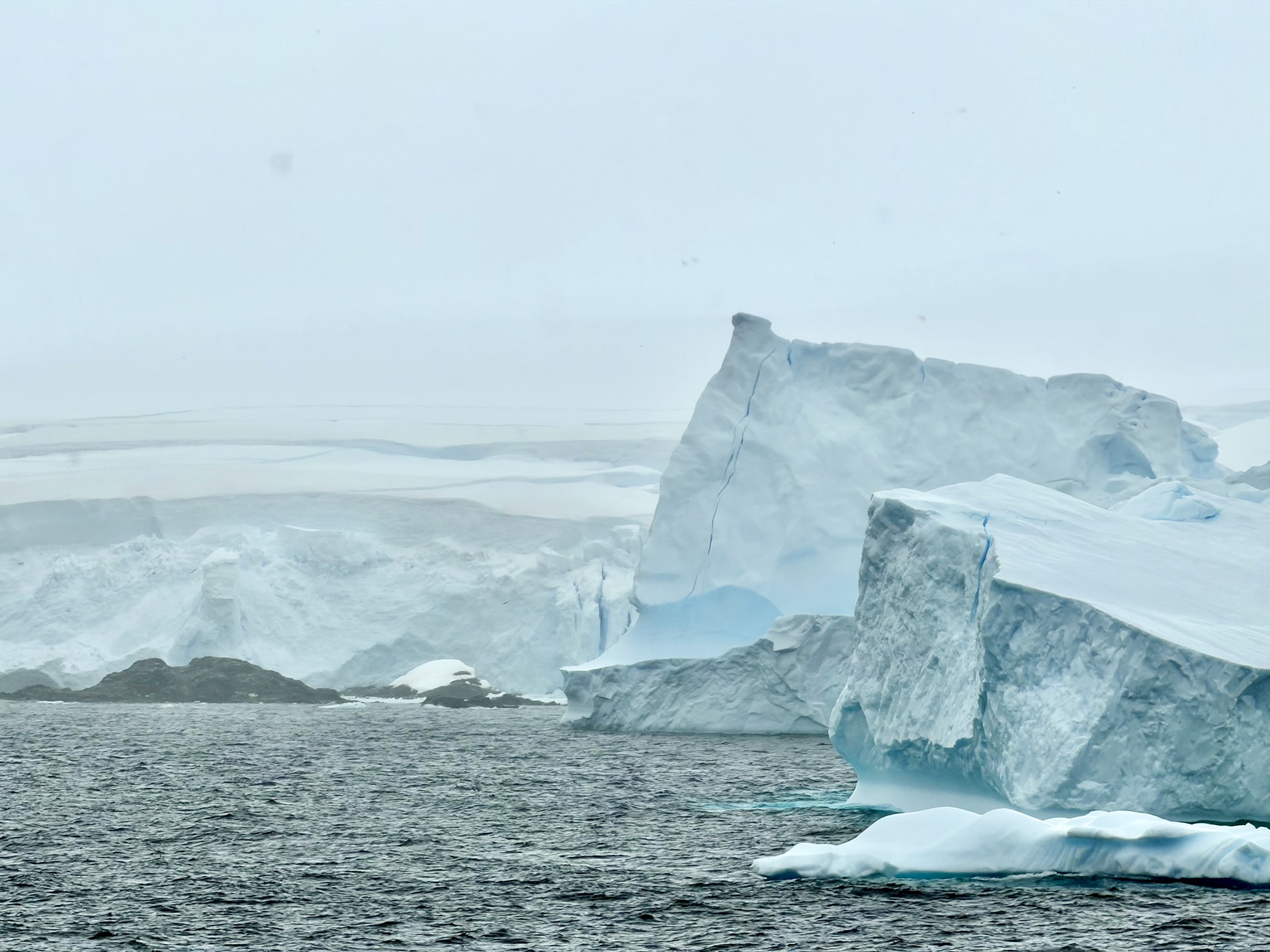 Tabular iceberg and Antarctic ice shelf Southern Ocean Large tabular iceberg floating near an Antarctic ice shelf in grey Southern Ocean waters