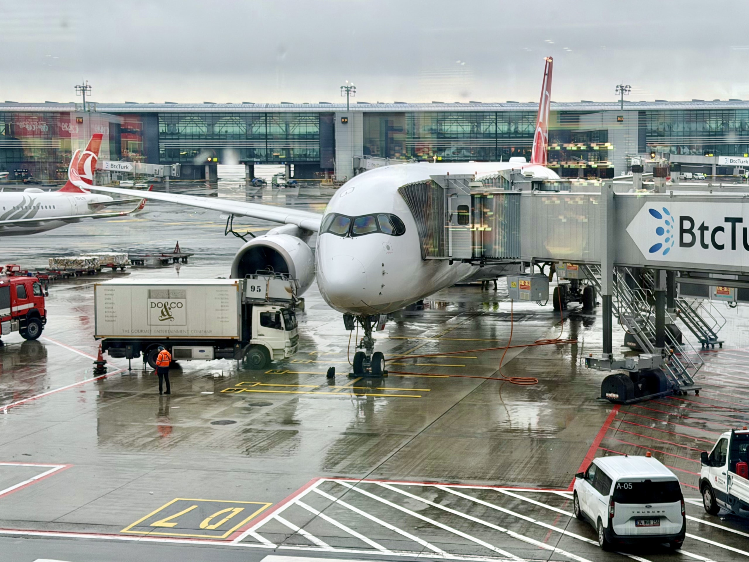 Turkish Airlines Airbus A350 at Istanbul Airport gate in rainy conditions, two hours after scheduled departure