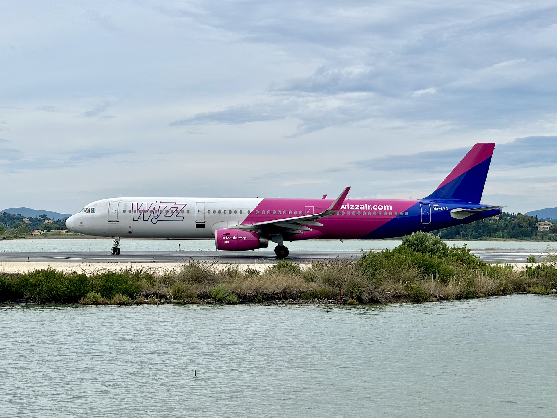 Wizz Air Airbus A321 taxiing at Corfu Airport CFU Wizz Air Airbus A321 taxiing at Corfu Airport with the characteristic lagoon and Mediterranean landscape in the background