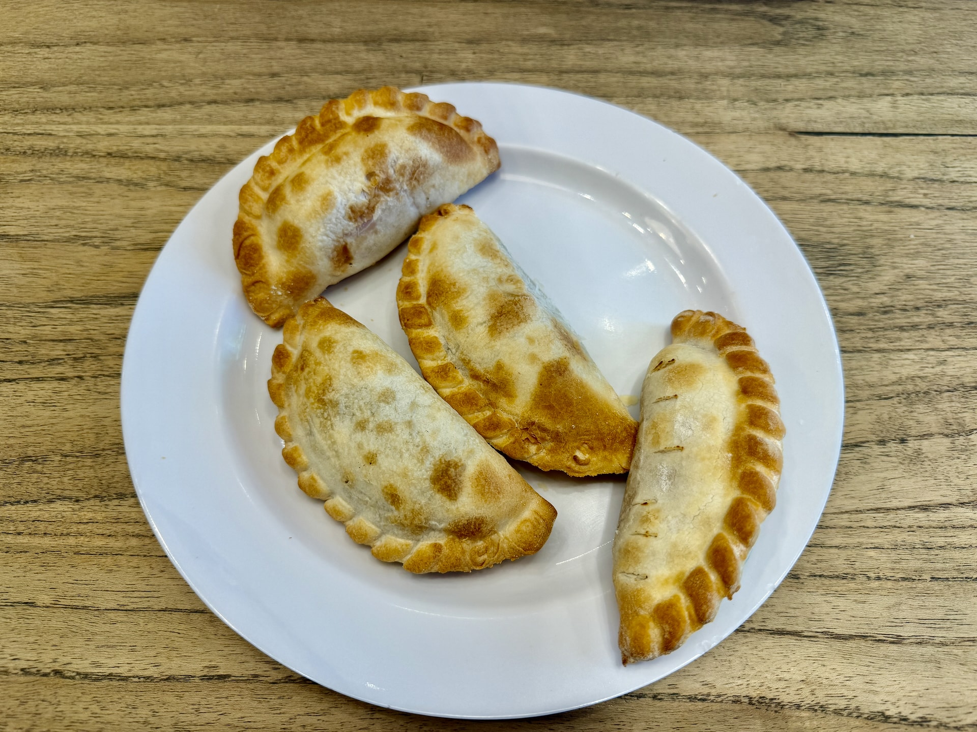 Empanadas at Vinnies Empanadas in Buenos Aires Four empanadas with differently crimped edges on a white plate at Vinnies Empanadas in Buenos Aires.