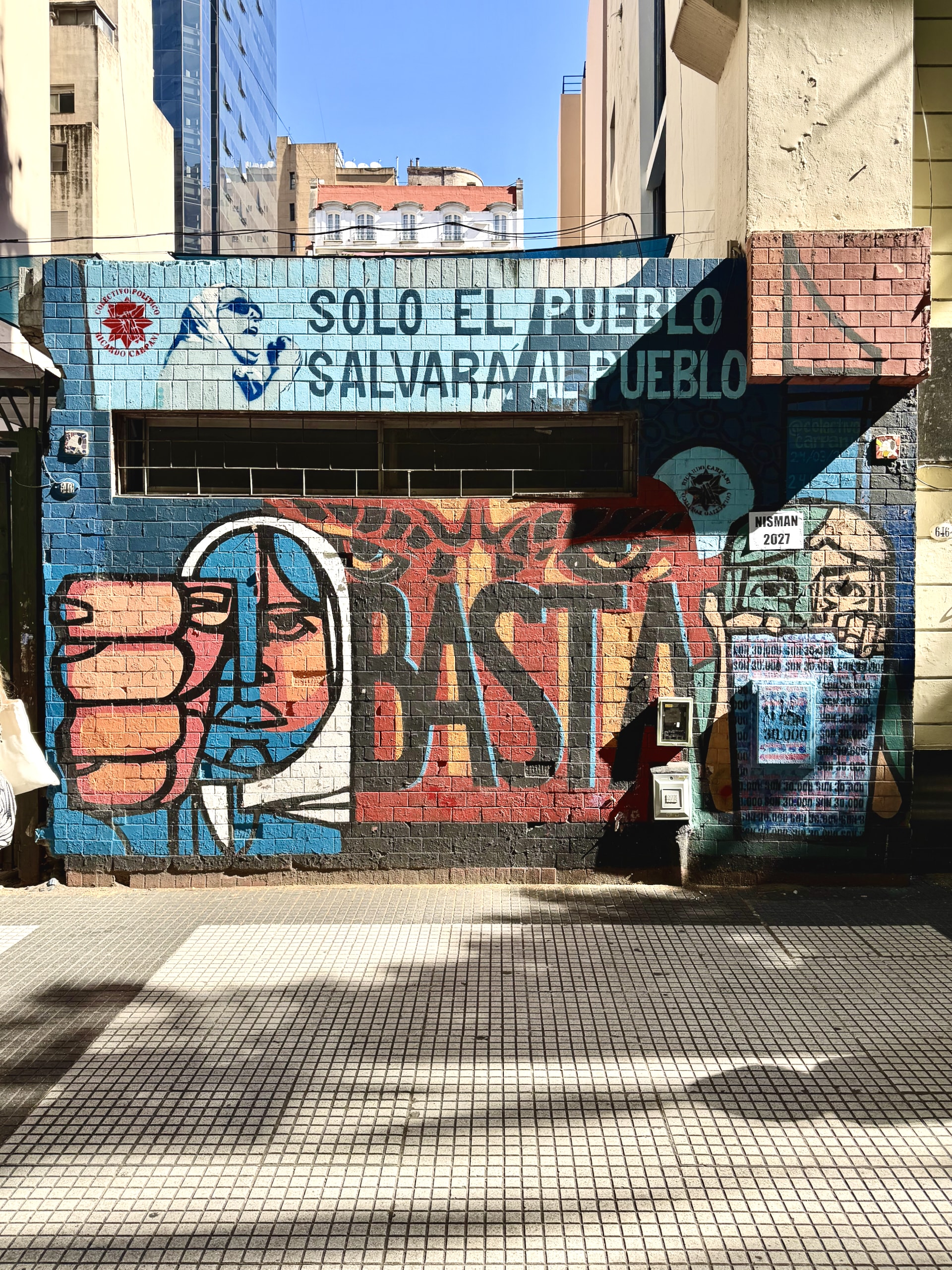 Street art with the white-headscarved women of Plaza de Mayo Street art in Buenos Aires showing a raised fist and a woman in a white headscarf, beside the words 'Solo el pueblo salvará al pueblo.'