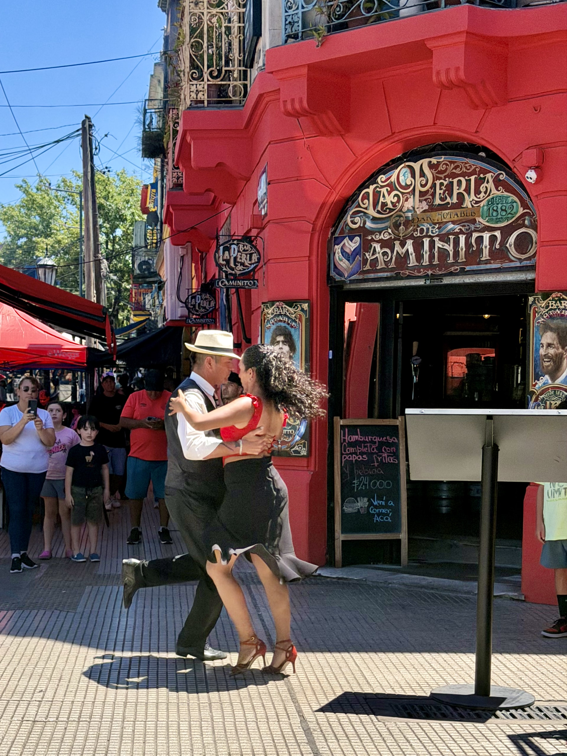 Street tango in La Boca, Buenos Aires A couple dancing tango on the street outside La Perla de Caminito in La Boca, a crowd of onlookers watching.