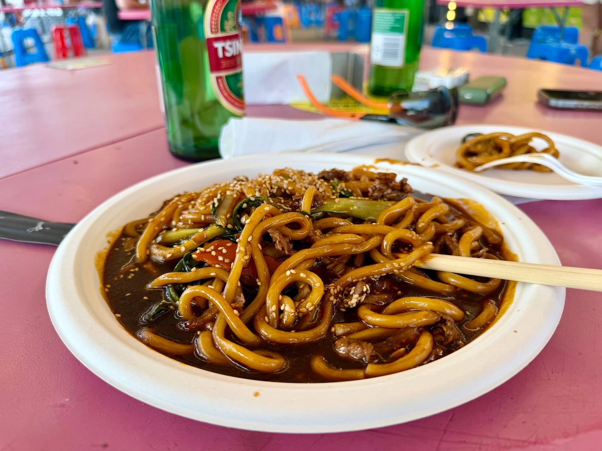 Beef udon noodles at Fully Night Market Budapest Beef udon noodles in dark sauce with sesame seeds and bok choy at Fully Night Market, chopsticks resting on the bowl.