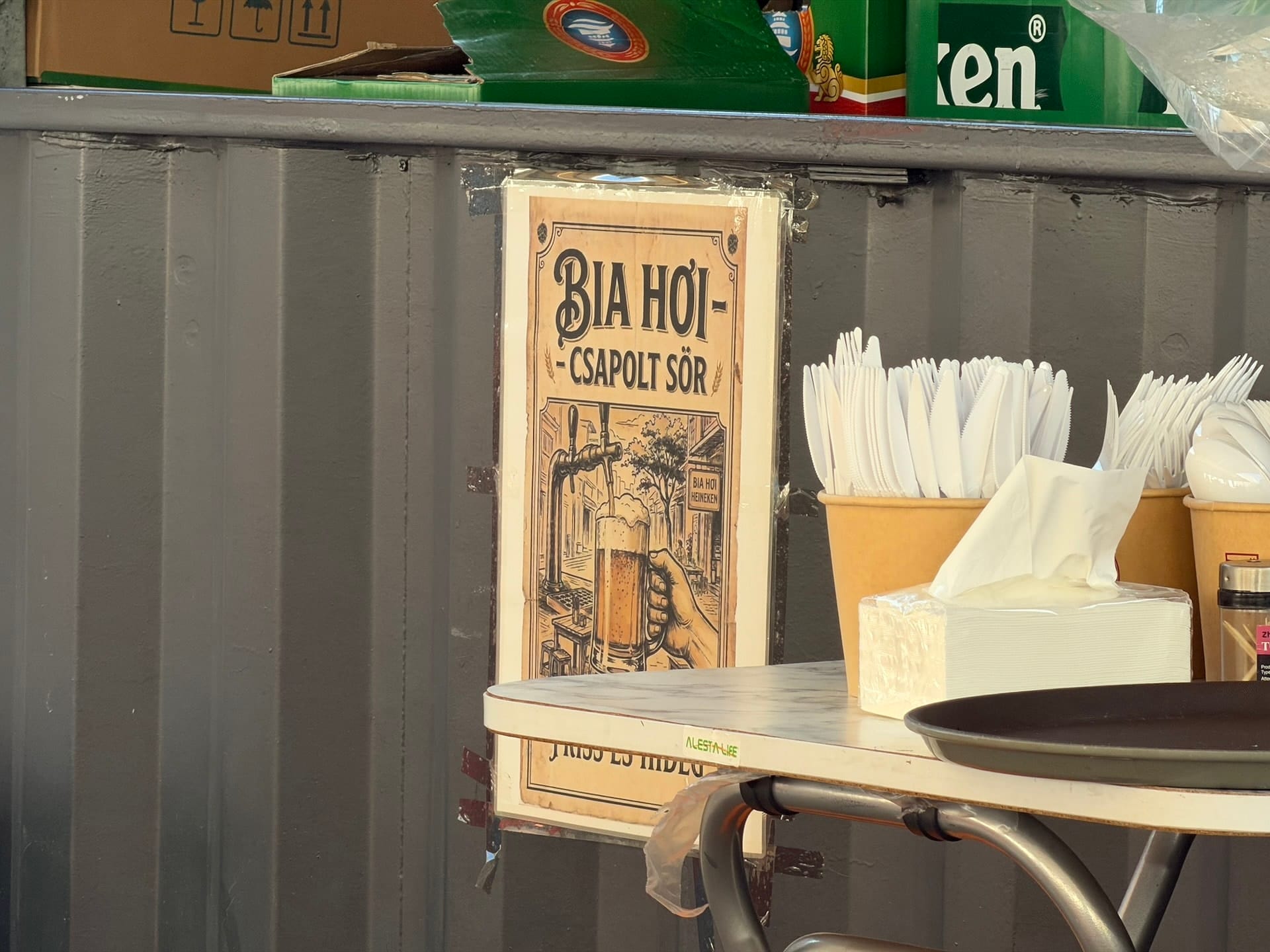 Bia hoi draft beer sign at Fully Night Market Budapest A Bia Hoi csapolt sor sign on a container wall at Fully Night Market, with Heineken crates stacked above it.