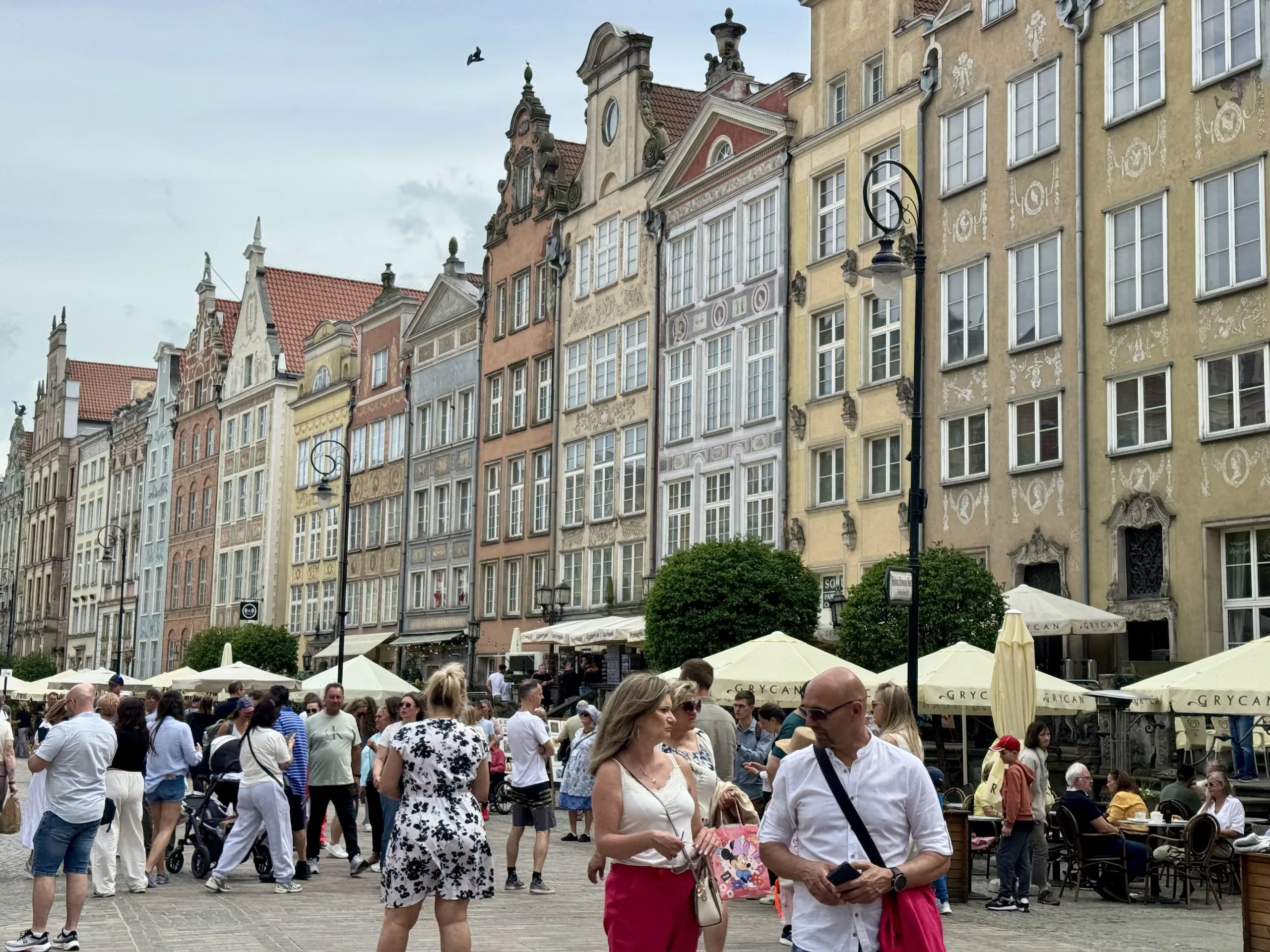 View from an upper-floor window over Długa Street in Gdańsk's Main Town, colorful step-gabled townhouses and banners lining the street below.