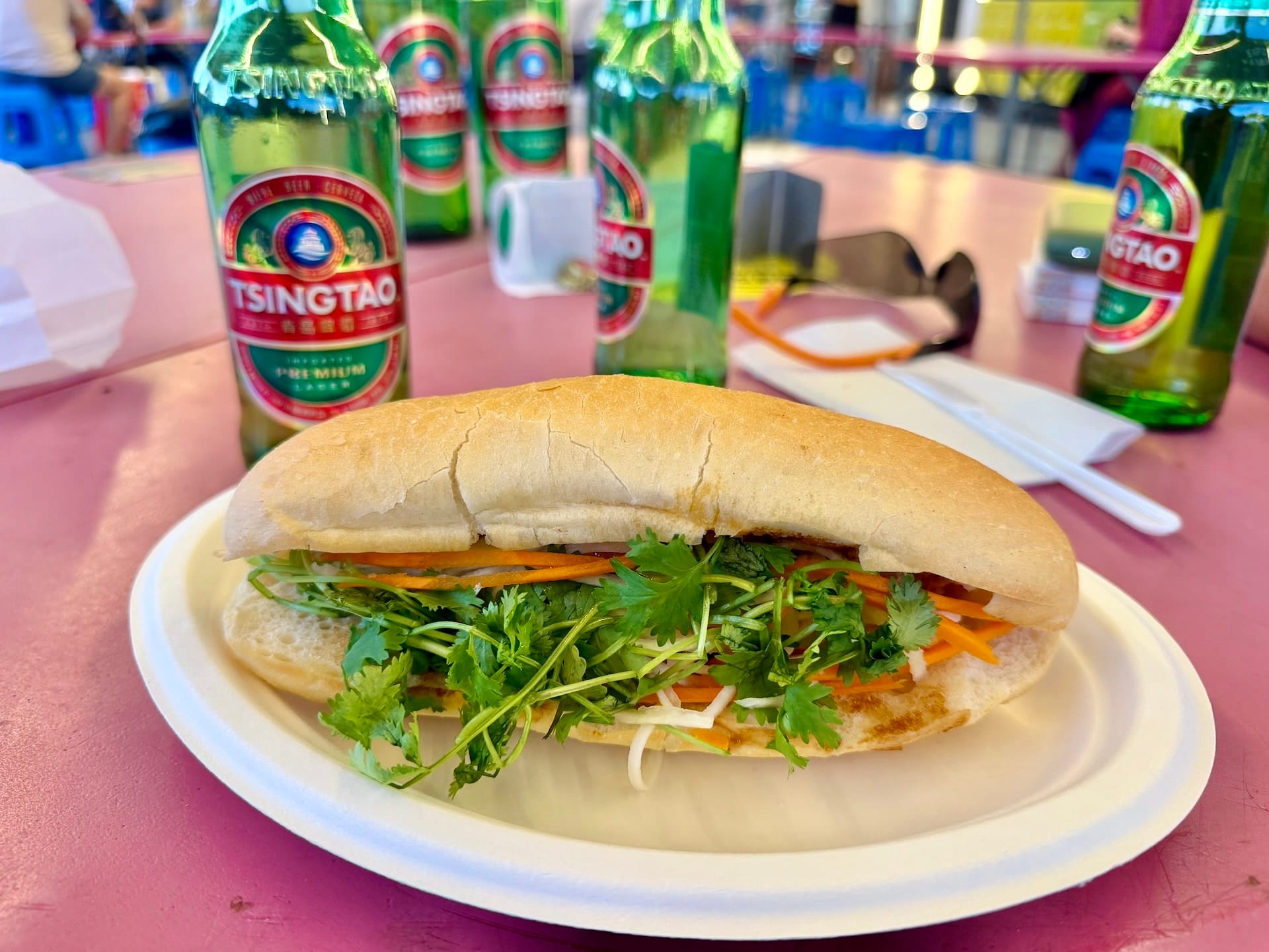 Meat-free banh mi at Fully Night Market Budapest A meat-free banh mi with cilantro and shredded carrot on a paper plate at Fully Night Market, Tsingtao bottles behind.