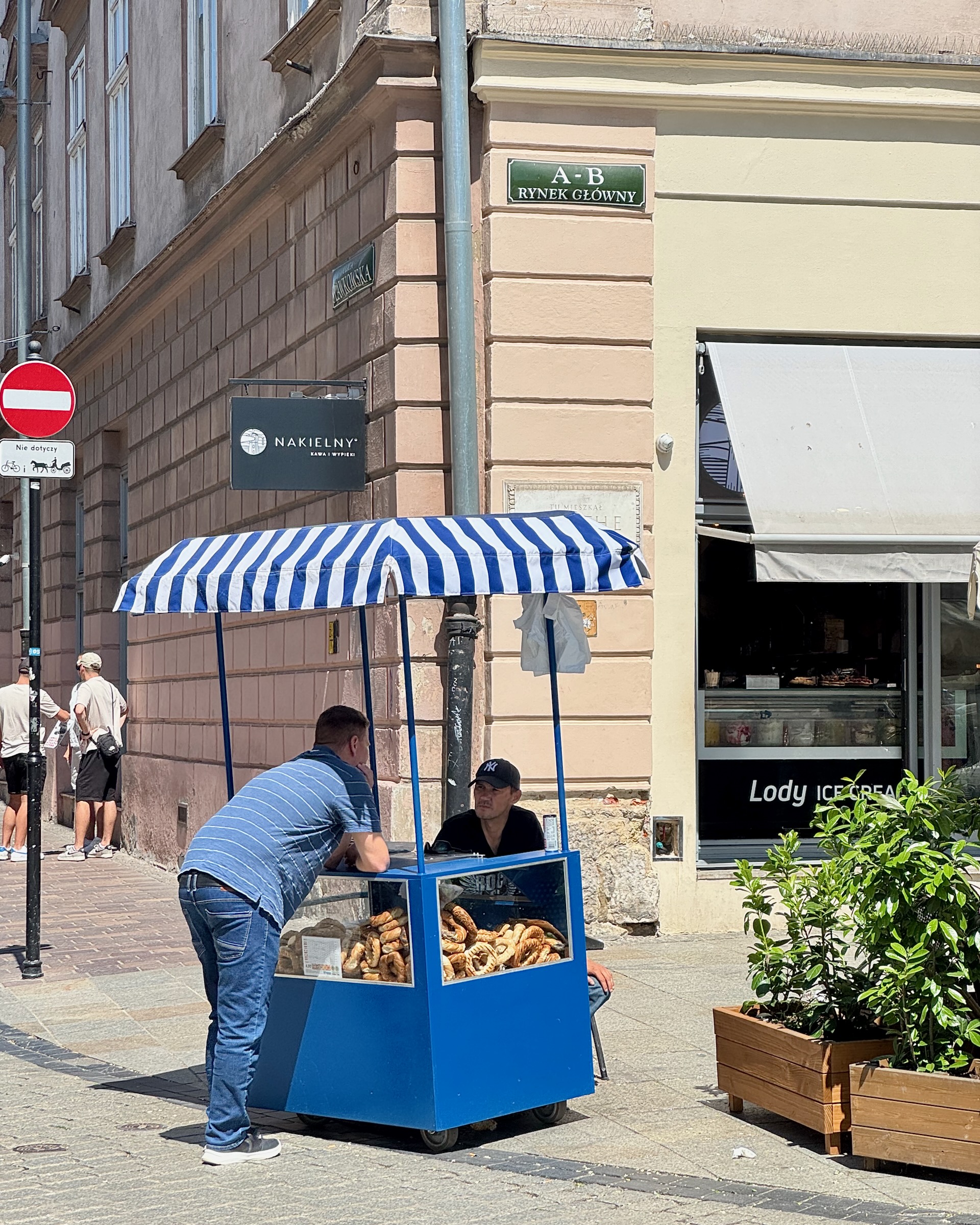 Blue-and-white striped obwarzanek cart on Rynek Główny, Krakow's ring-shaped bread rolls on display