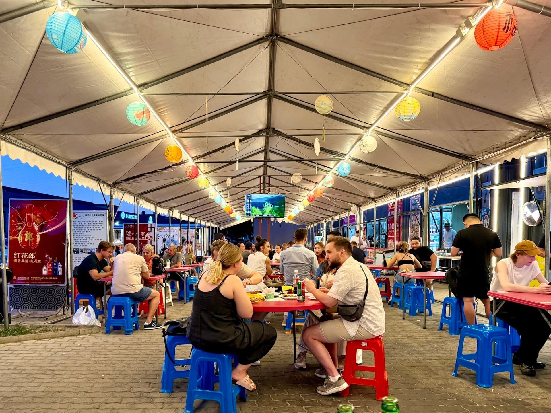 Paper lanterns lighting the dining tent at Fully Night Market Colored paper lanterns and string lights strung along the roof of a busy dining tent at Fully Night Market.