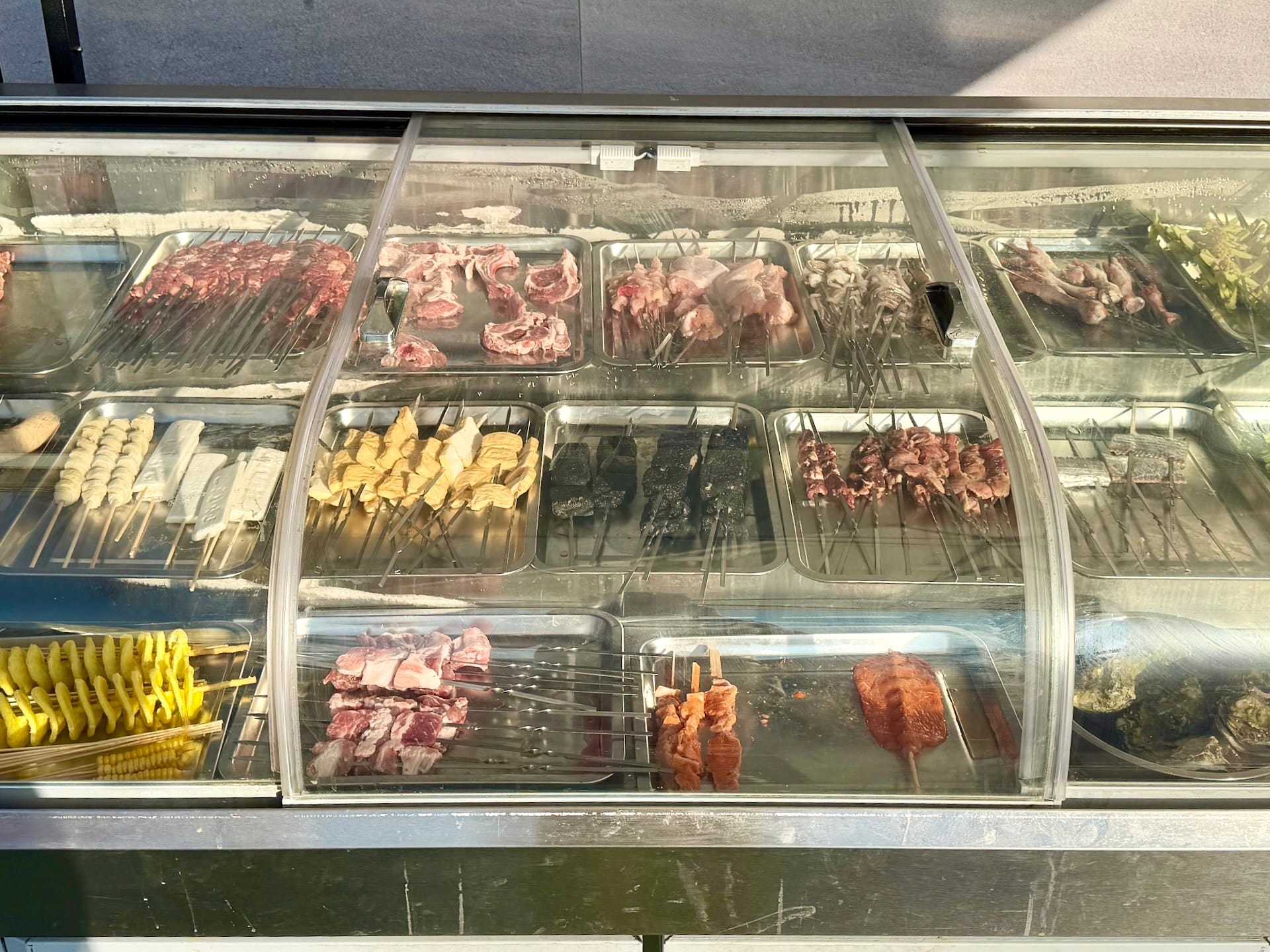 Raw skewer counter at Fully Night Market Budapest Chilled counter of raw skewers at Fully Night Market, with meat, tofu, vegetables and spiral potato on sticks.