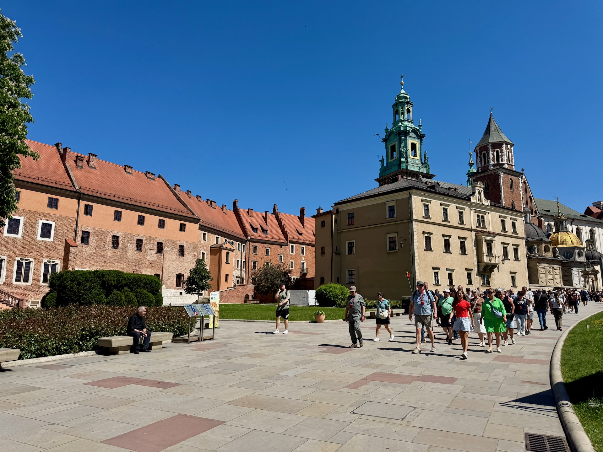 Tourists walking through the Wawel courtyard toward the cathedral's green-domed towers