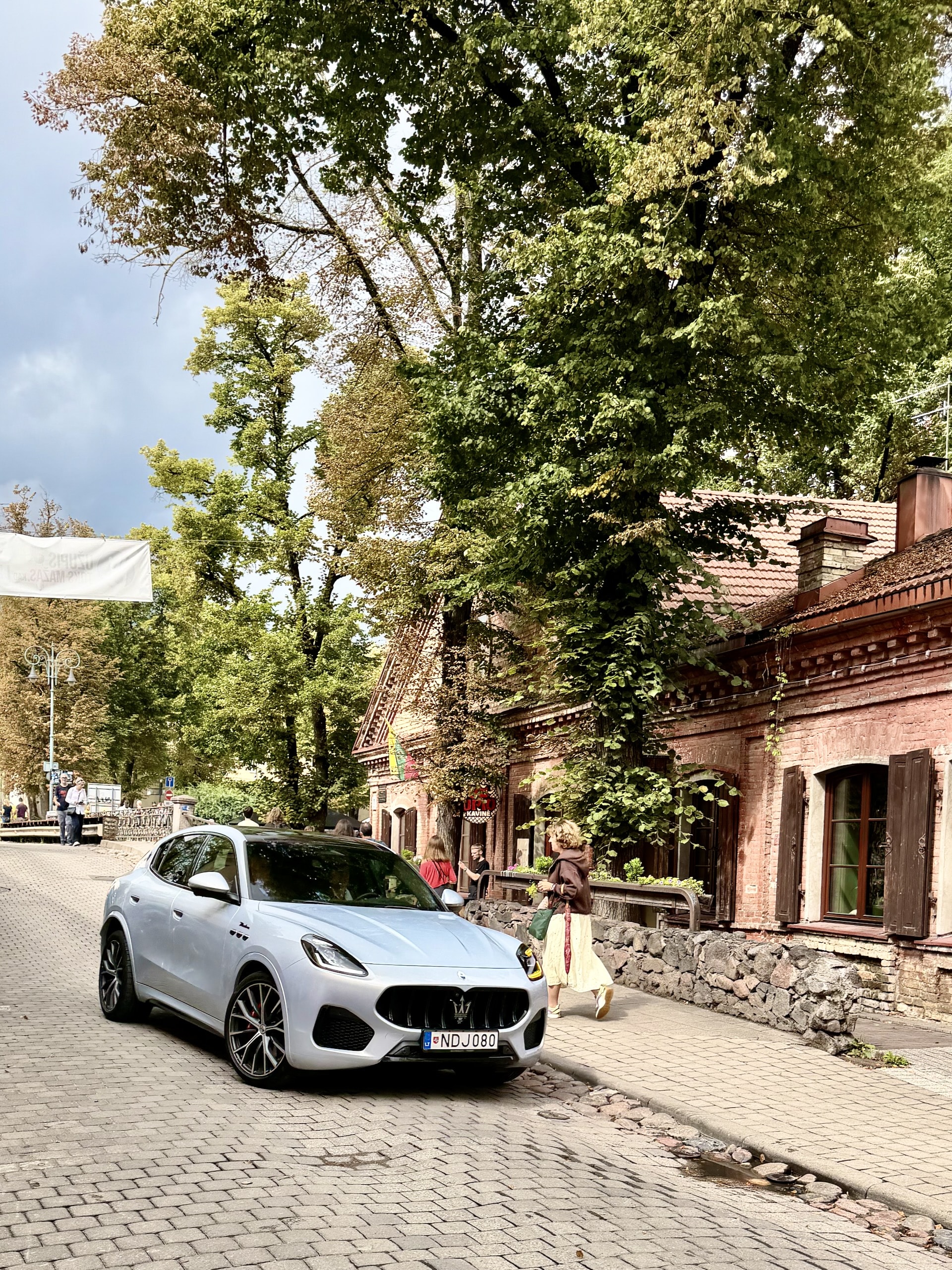 Maserati on a street in Užupis Vilnius A Maserati SUV on a cobbled street in Užupis, Vilnius, in front of an ivy-covered red brick house.