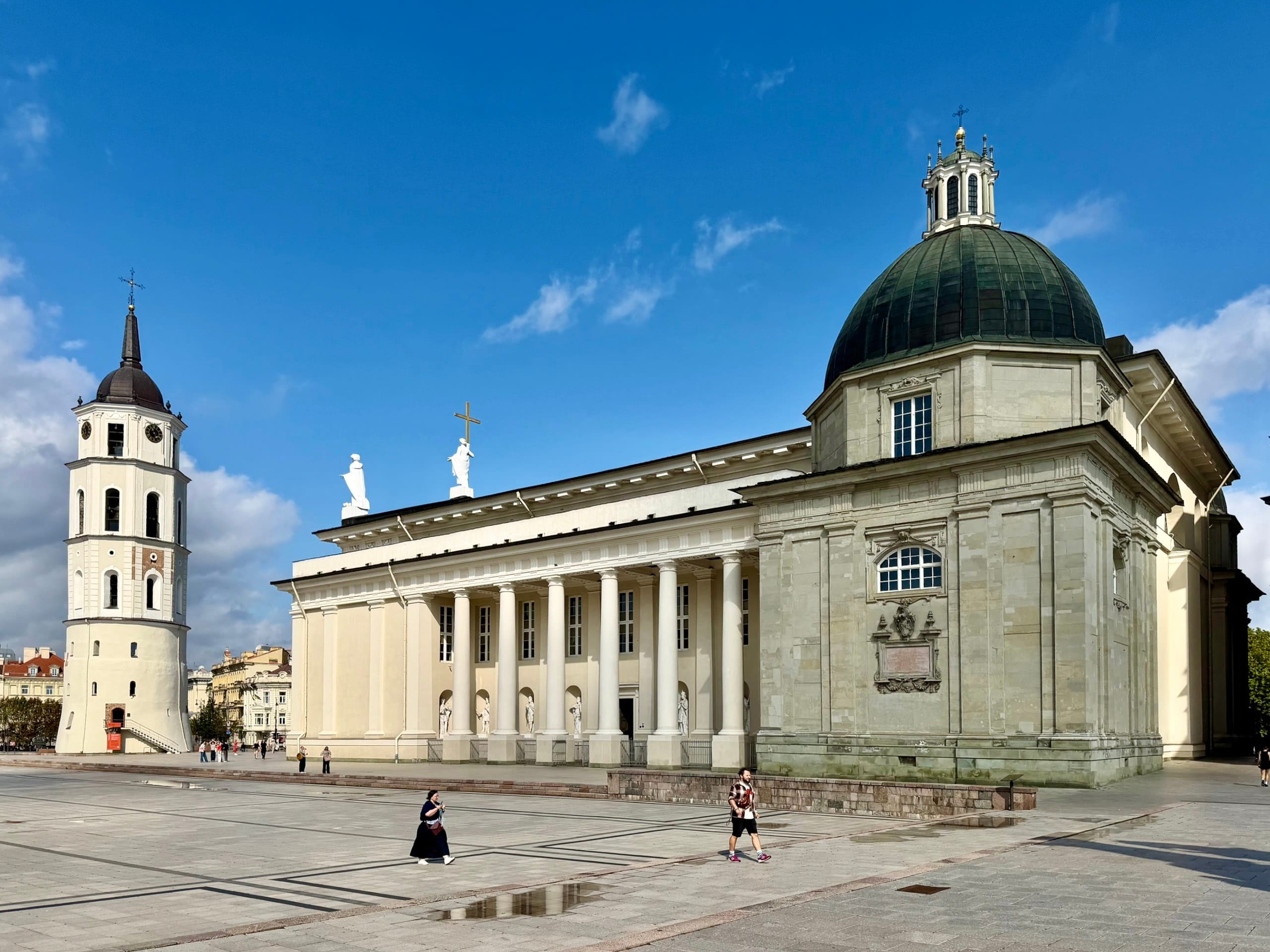 Vilnius Cathedral and its free-standing white bell tower on Cathedral Square under a blue sky.