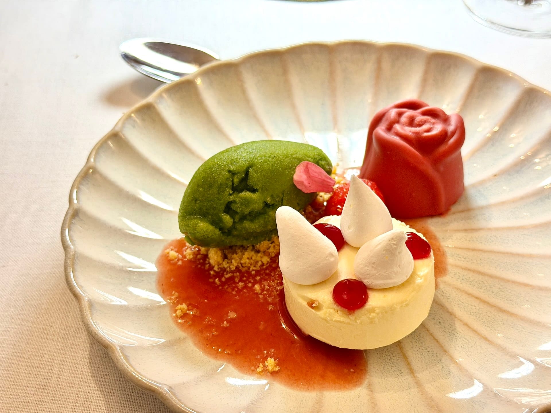 Wild strawberry legumina dessert at Ertlio Namas Dessert plate with basil sorbet, a rose-shaped red confection and elderflower cream with meringues and redcurrants.