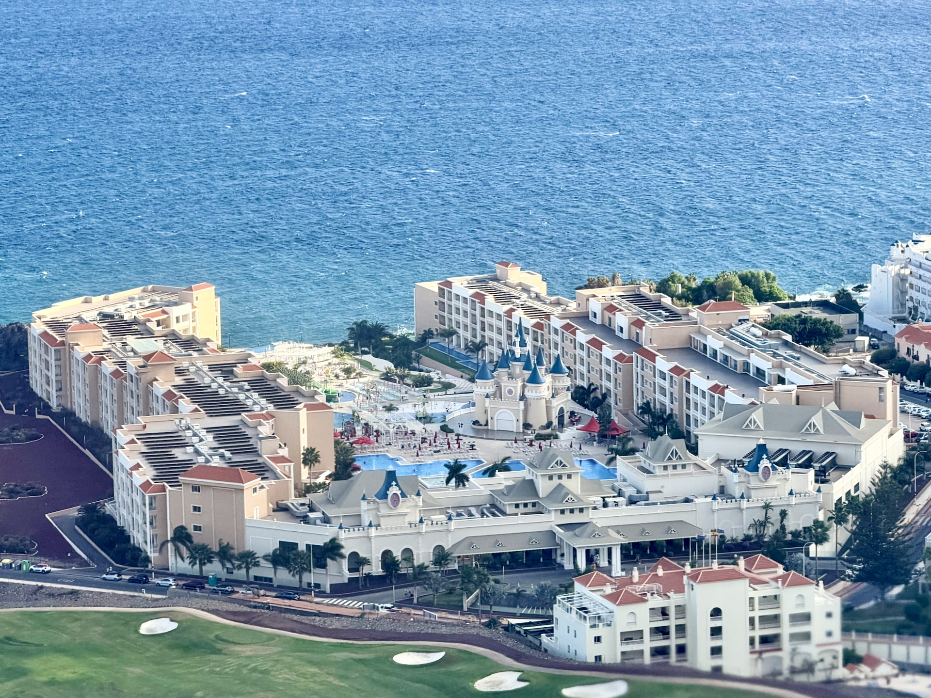 Aerial view from the plane of a large resort complex with a fairytale castle facade, pools and a golf course on the south coast of Tenerife