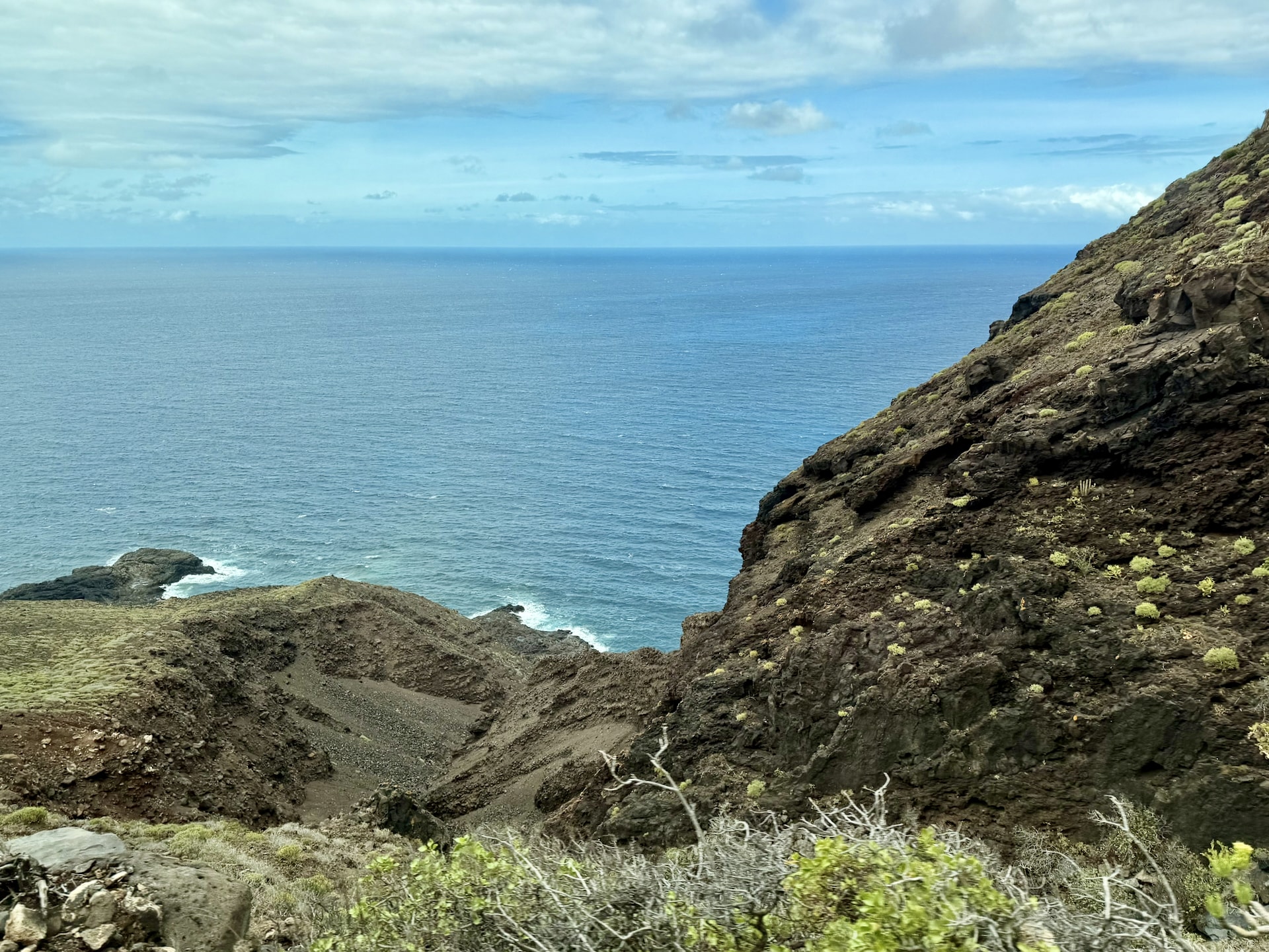 Atlantic view over steep green slopes and a rocky coastline on the way to Punta de Teno