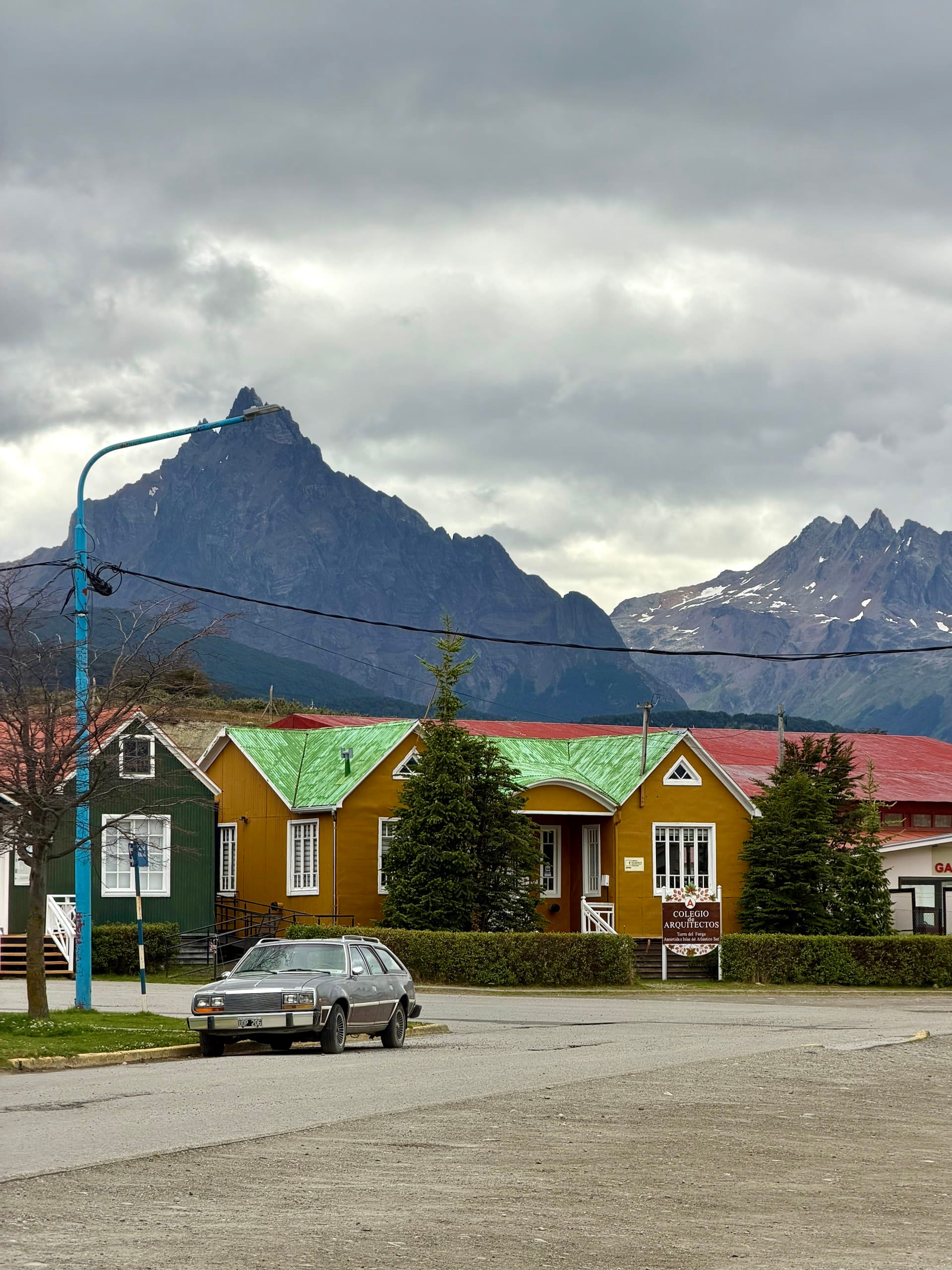 Colorful wooden houses of the Colegio de Arquitectos in Ushuaia with the pointed peak of Monte Olivia behind