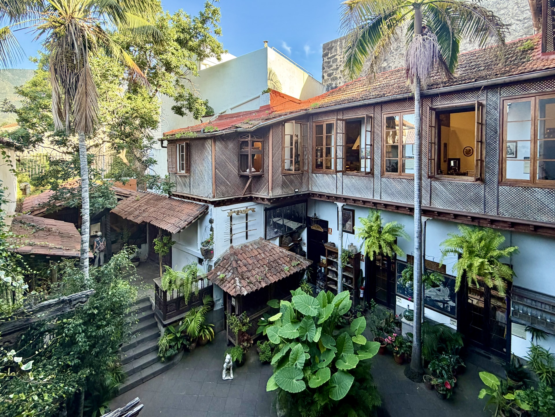 Courtyard of the Casa de los Balcones in La Orotava, with wooden galleries, a tiled roof, palm trees and potted plants