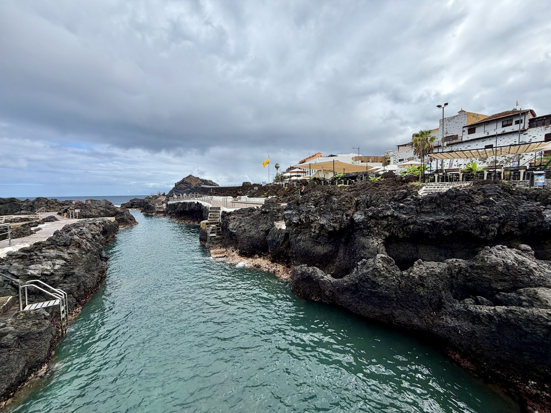 El Caletón natural pools in Garachico, a channel of turquoise seawater between black lava rocks with the town behind