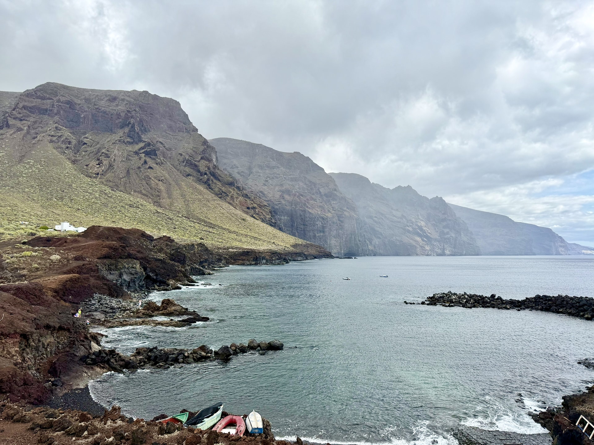 Small cove at Punta de Teno with fishing boats on the shore, a breakwater and the Teno cliffs behind