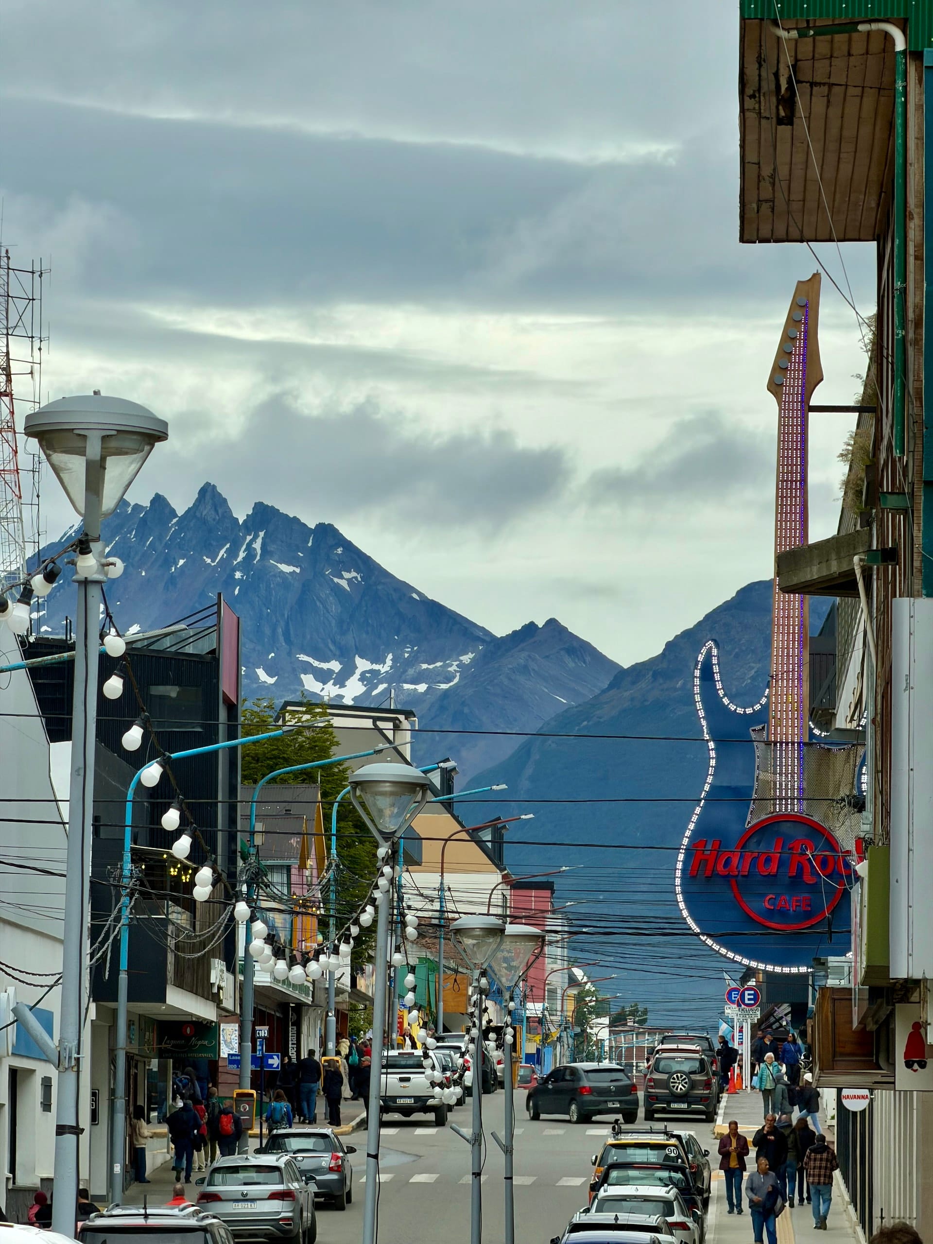 Hard Rock Cafe guitar sign on Avenida San Martín in Ushuaia, mountains at the end of the street