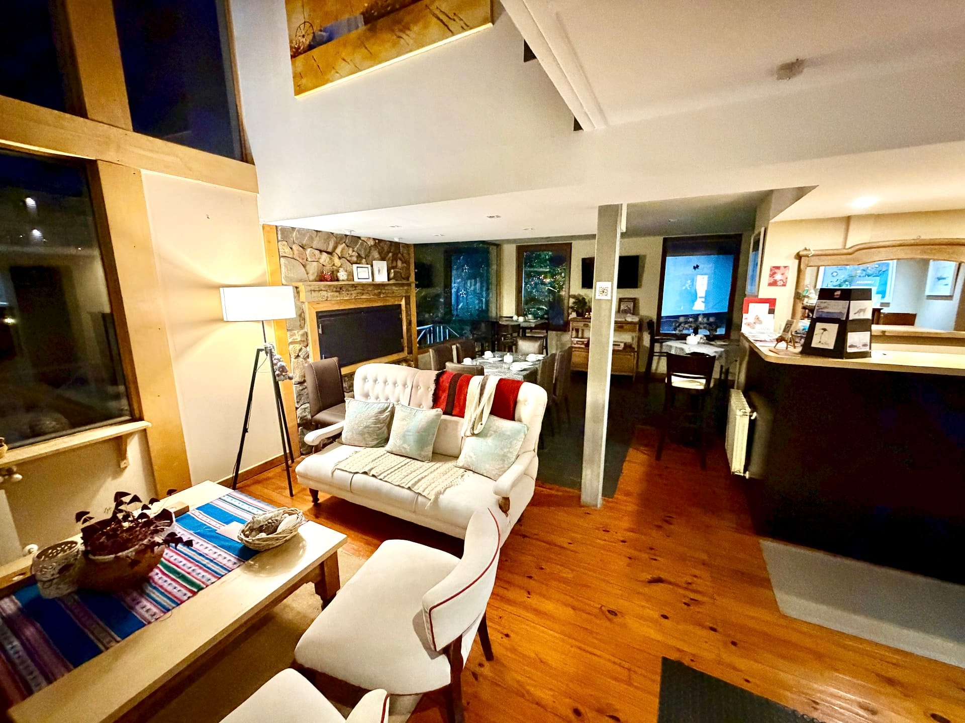 Warm lounge at Hostería Foike with a white sofa, wooden floors, a stone wall and a breakfast area