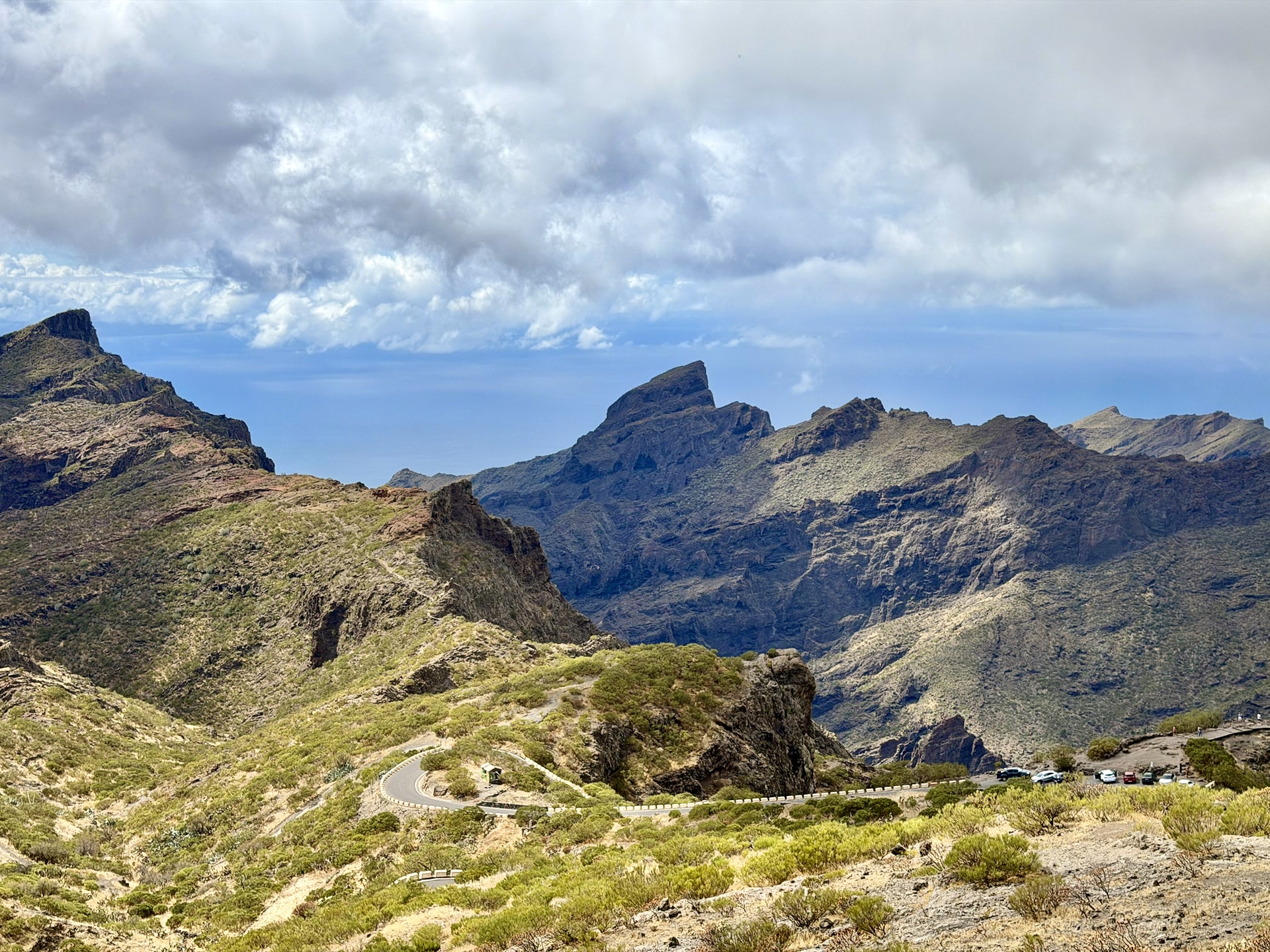The Masca valley from Mirador de Cherfe, jagged Teno peaks and a winding road under a partly blue sky