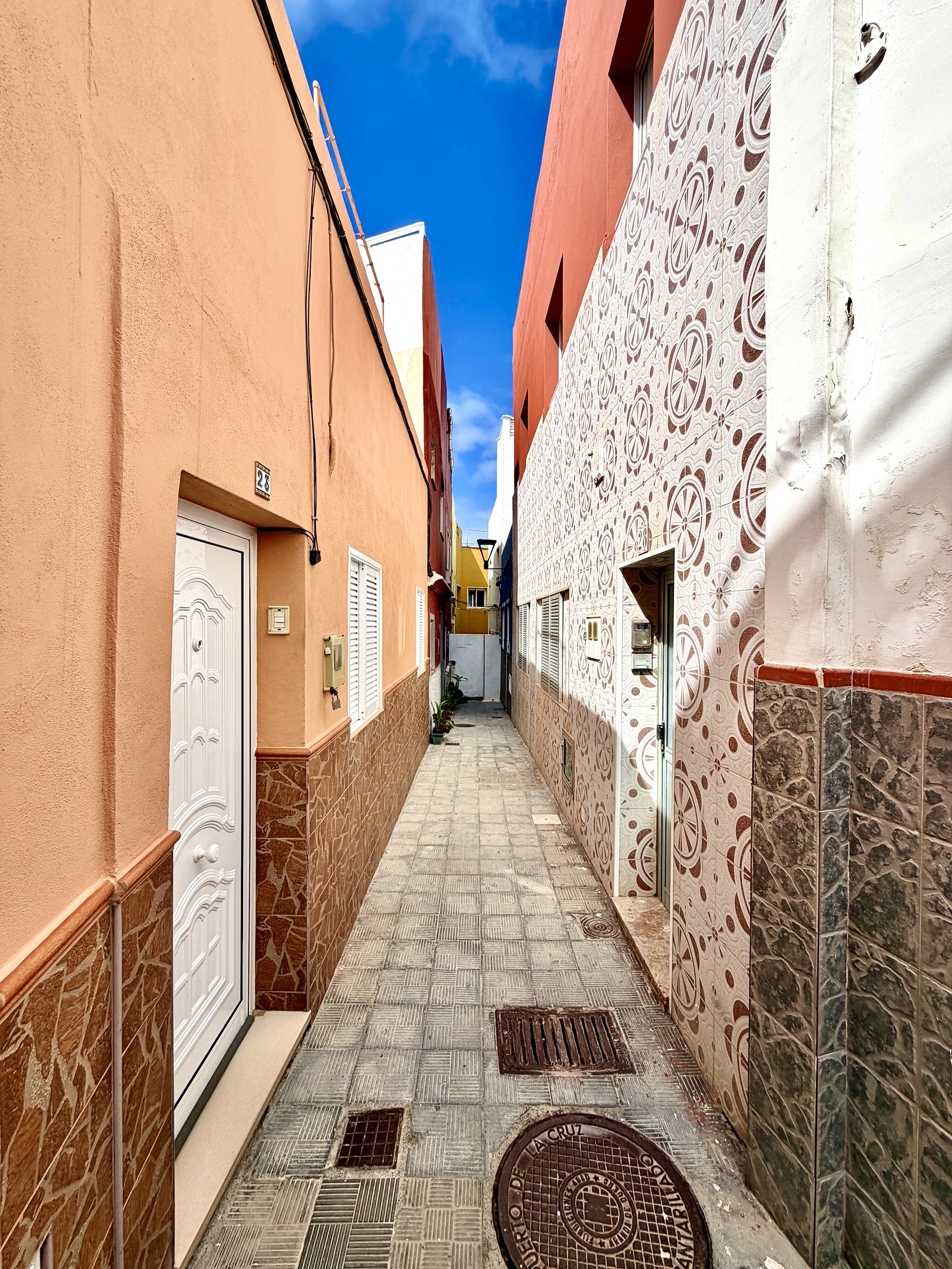 Narrow paved alley in Punta Brava, Puerto de la Cruz, with one wall covered in patterned red and white tiles