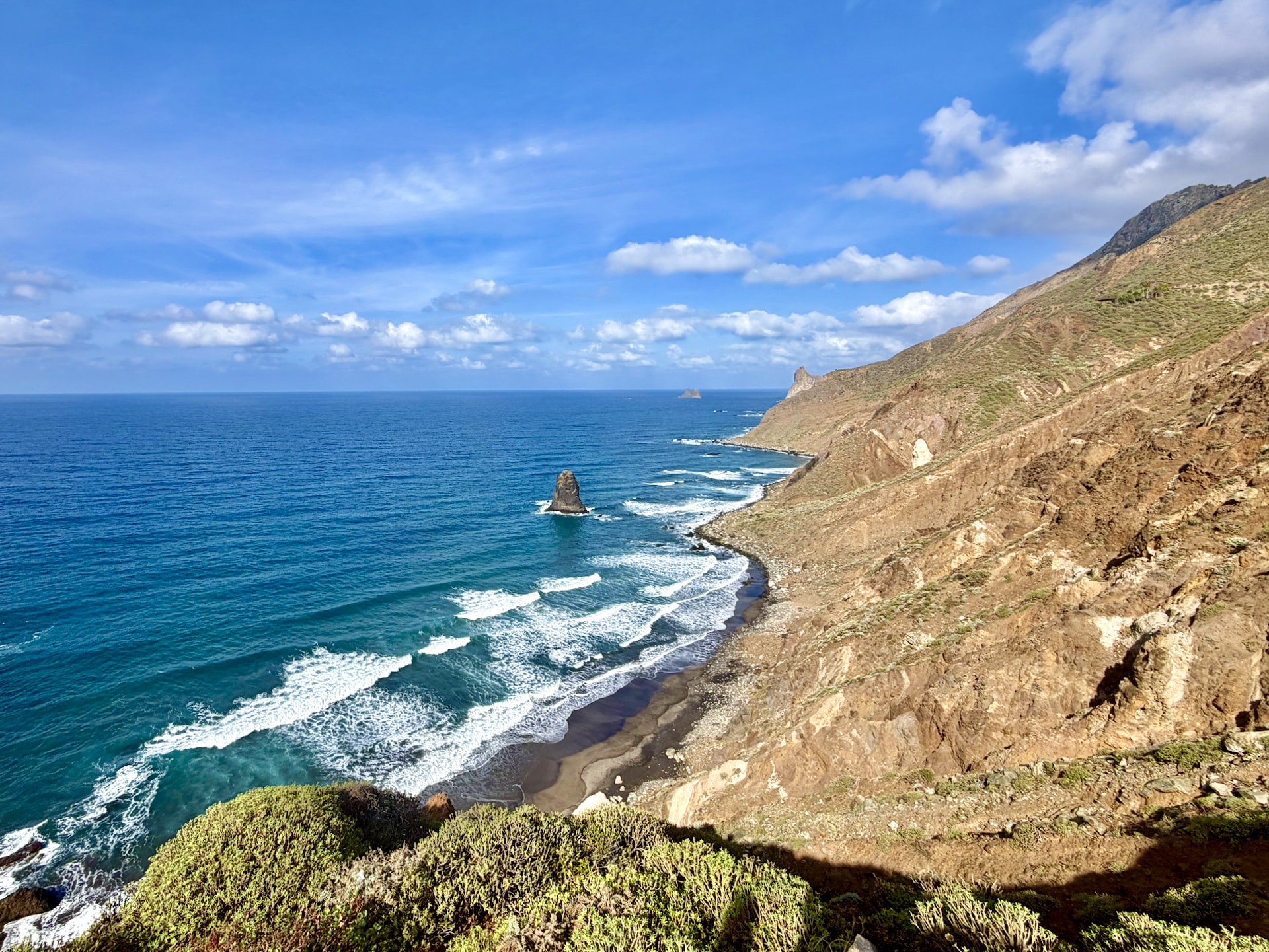 Steep slopes of the Anaga mountains dropping to a black sand beach and the Atlantic, with a rock stack offshore near Benijo