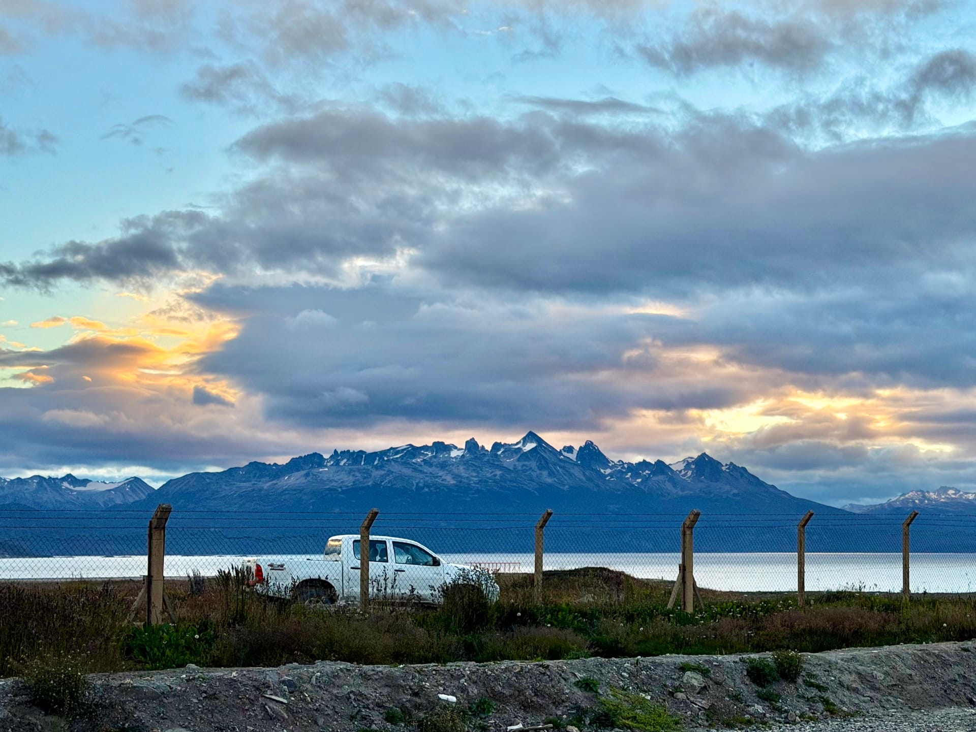 Snow-capped Martial Mountains rising behind the Beagle Channel at Ushuaia airport, a white pickup truck in the foreground