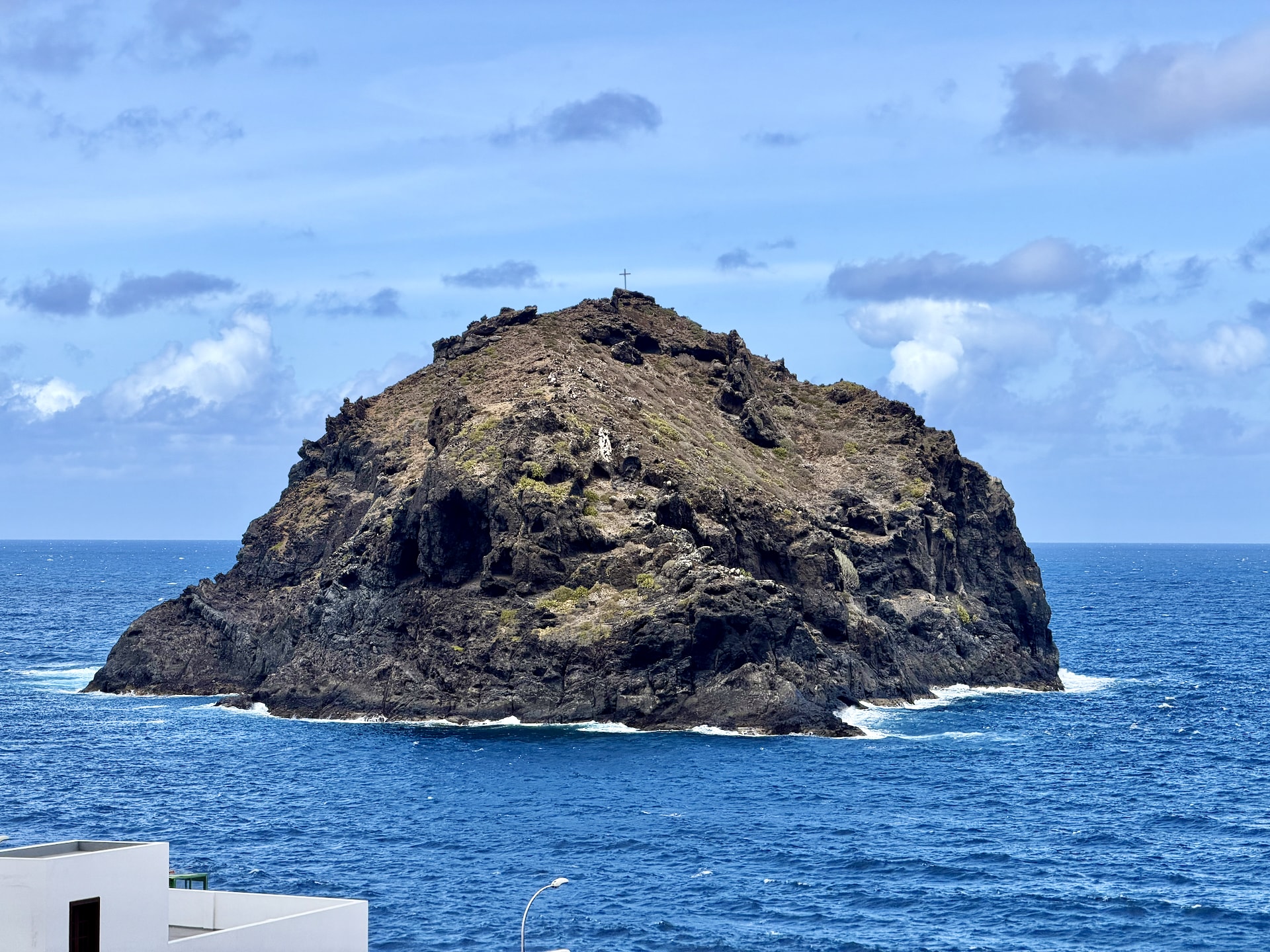 The Roque de Garachico, a rocky islet topped with a cross, rising from the deep blue sea off Garachico