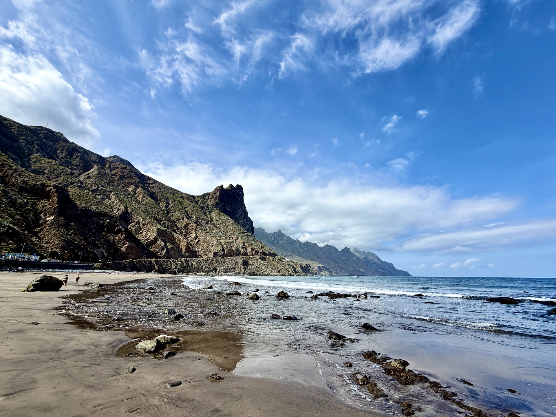 Roque de las Bodegas beach in the Anaga mountains Wide beach of dark sand and rocks at Roque de las Bodegas in Anaga, below steep mountains and a rock spire under a blue sky