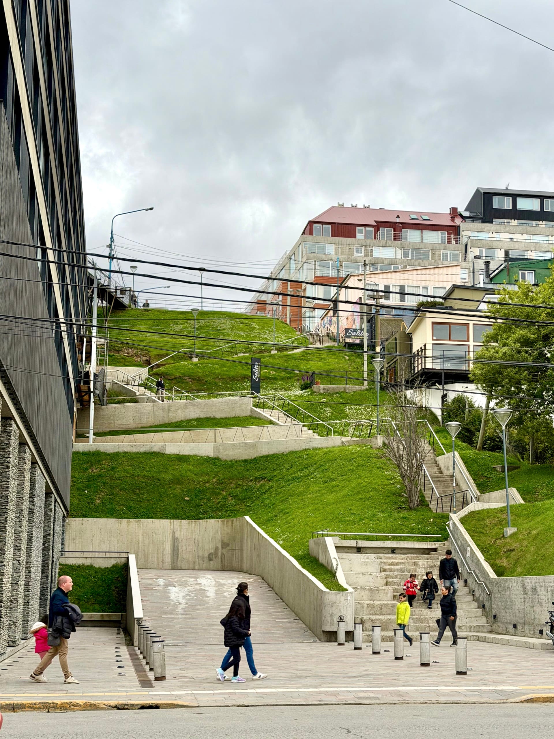 Concrete stairways and grassy terraces leading down the hillside toward the waterfront in Ushuaia