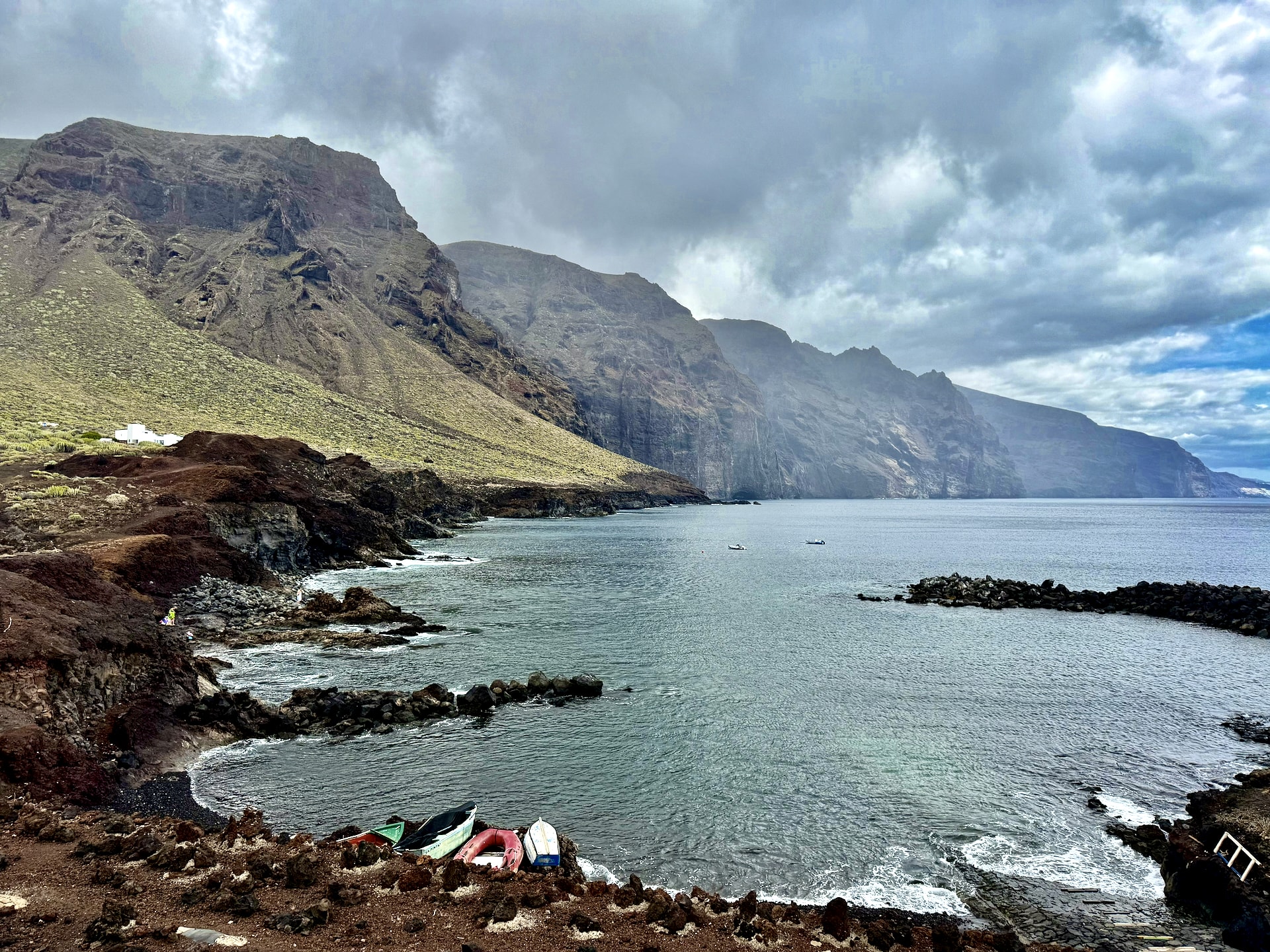Swimming cove by the fishing boats at Punta de Teno Small cove at Punta de Teno with fishing boats pulled up on the rocks, calm gray water and the Los Gigantes cliffs fading into cloud