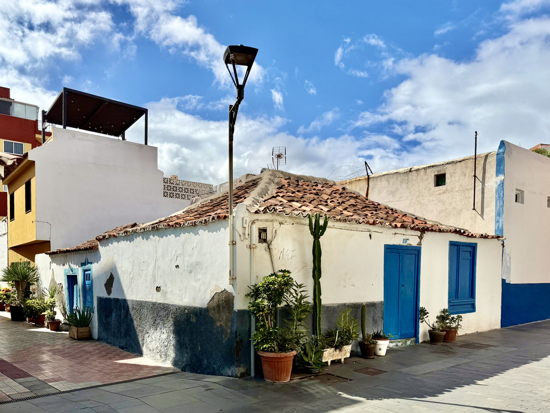 Small white single-story house with blue doors, a terracotta tile roof and potted plants on Calle Mequínez in La Ranilla, Puerto de la Cruz