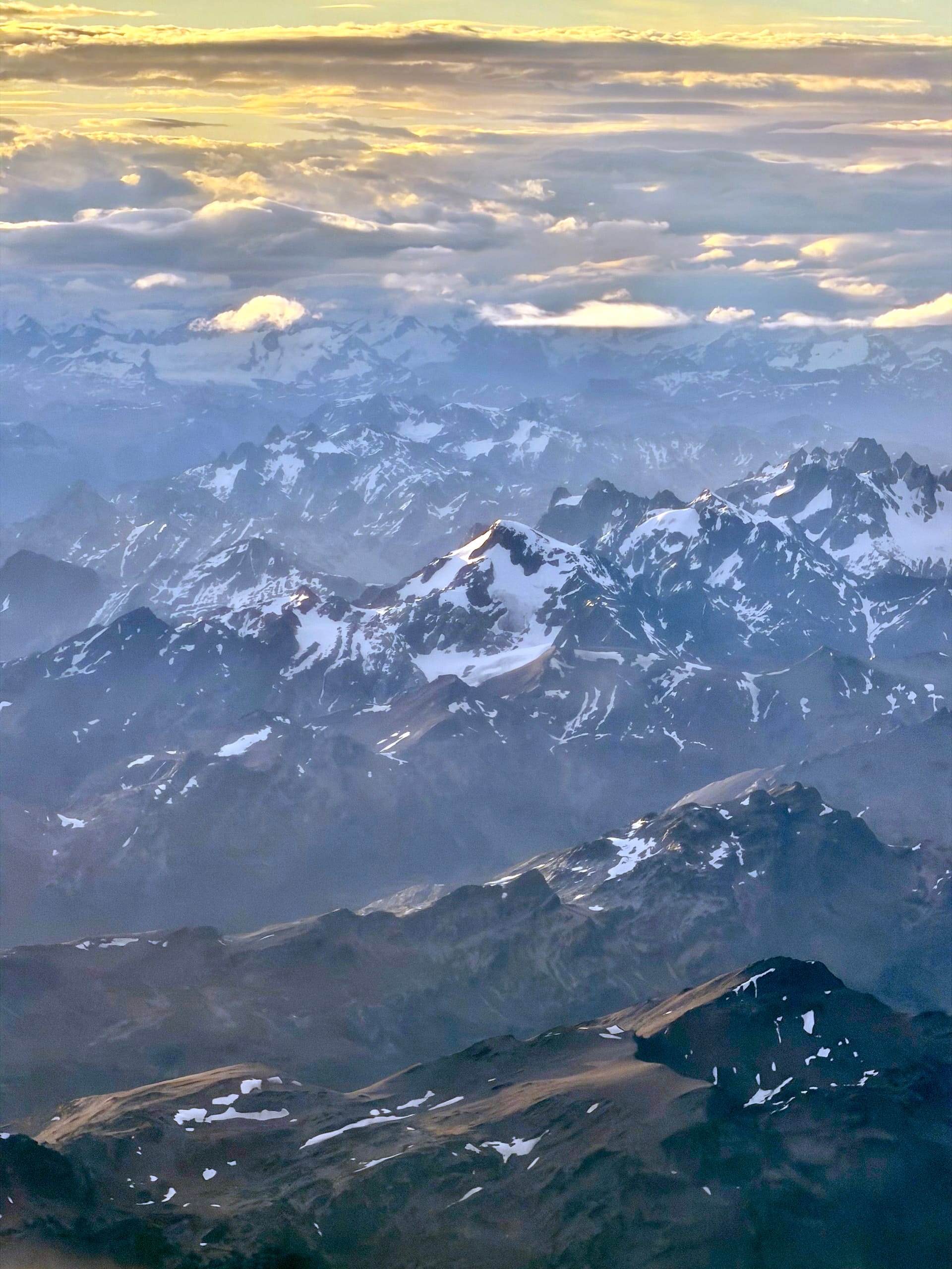 Snow-streaked peaks of Tierra del Fuego under low clouds, seen from the right-hand window on the flight into Ushuaia