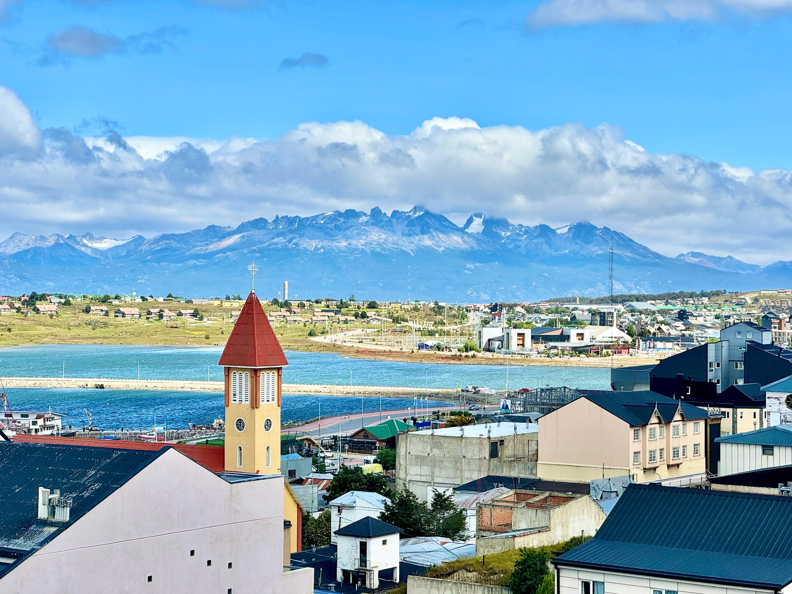 Ushuaia rooftops and the yellow bell tower of Nuestra Señora de la Merced church, the bay and snow-capped mountains beyond